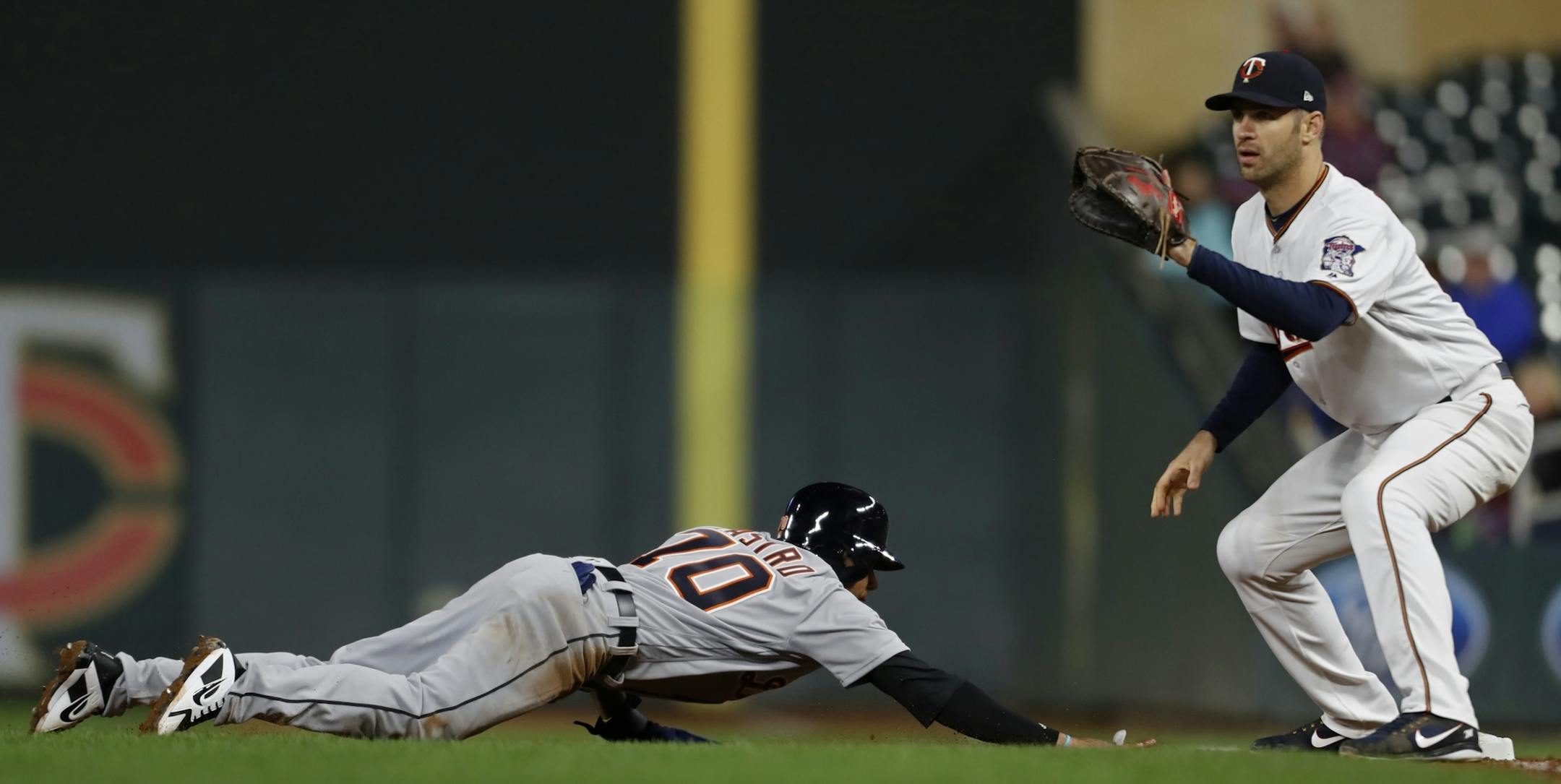 Tigers Harold Castro(70) is held to 1st base by Joe Mauer in 8th inning.
