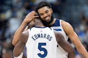 Anthony Edwards (5) of the Minnesota Timberwolves hugs Karl-Anthony Towns late in the fourth quarter on Monday at Ball Arena in Denver.