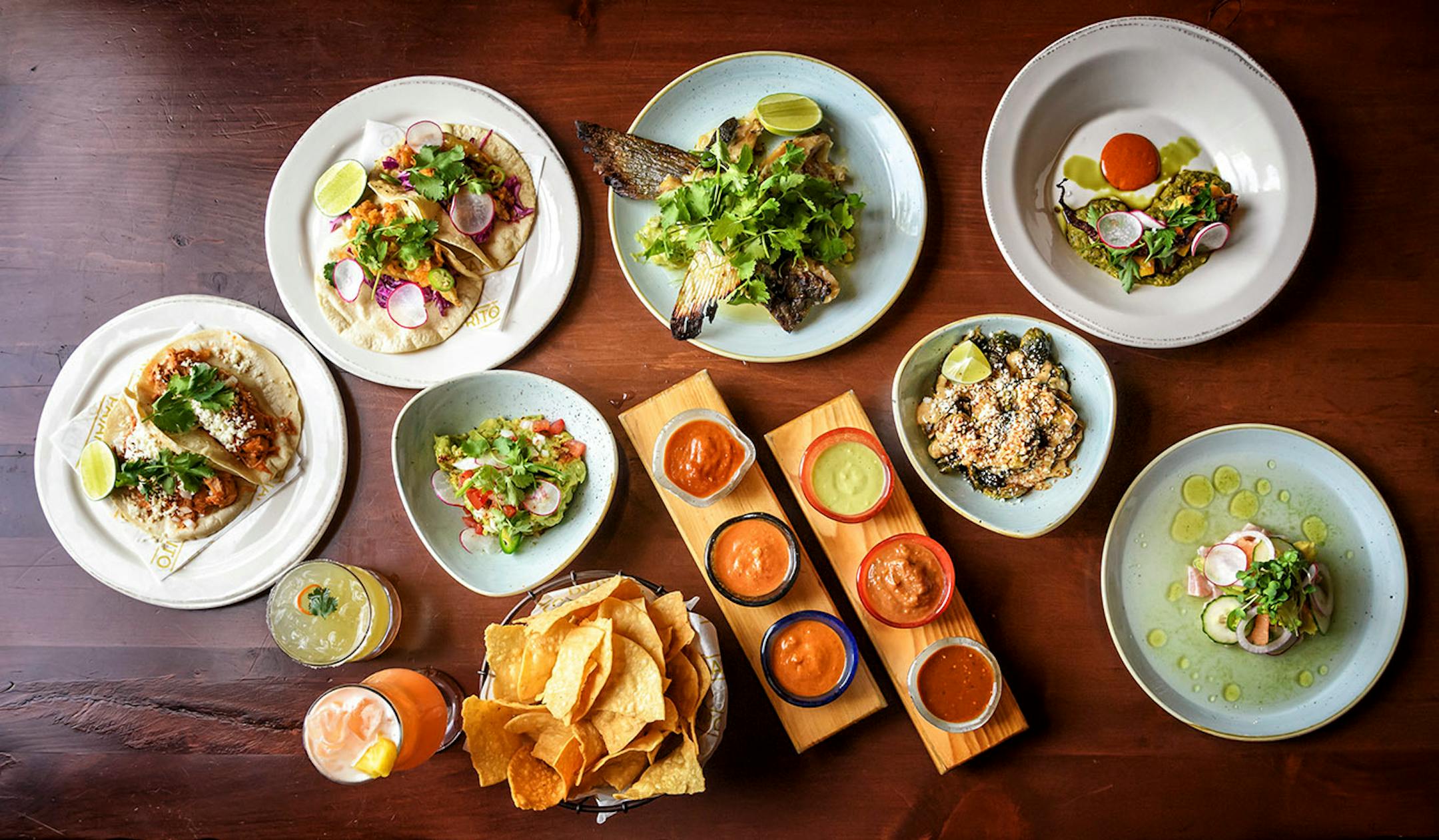 Clockwise from top left: Chicken Tinga tacos, Smelt tacos, the weekly fish special Grilled Halibut Collar, Grilled Octopus, Aguachile, Brussels Sprouts, Salsa and chips — Ancho-Guajillo, Charred Tomato, Avocado-Serrano, Arbol Cashew, Chipotle, Habanero, Cocktails "If You Like Pina…Ah Screw It" and Habanero Cilantro Margarita, Guacamole.