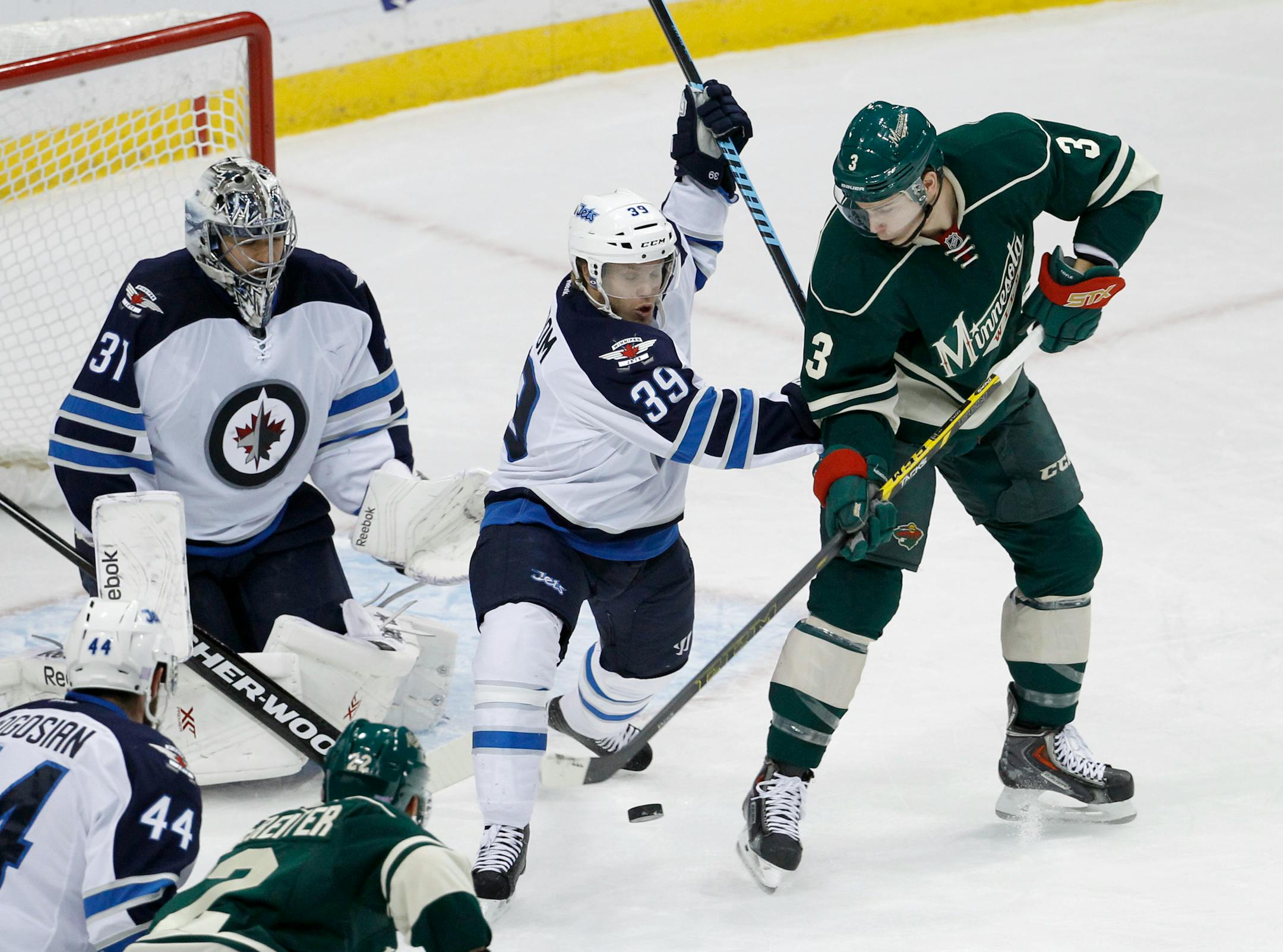 Minnesota Wild center Charlie Coyle, right, reaches for the puck under Winnipeg Jets defenseman Tobias Enstrom (39), of Sweden, as Jets goalie Ondrej Pavelec (31), of the Czech Republic, covers the net during the first period of an NHL hockey game in St. Paul, Minn., Sunday, Nov. 16, 2014. (AP Photo/Ann Heisenfelt)