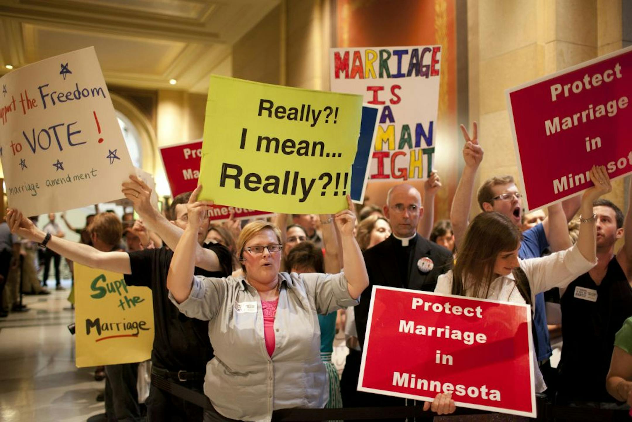 Demonstrators both for and against a gay marriage amendment chanted and held signs outside the entrance to the House chambers during the session Thursday afternoon at the State Capitol.