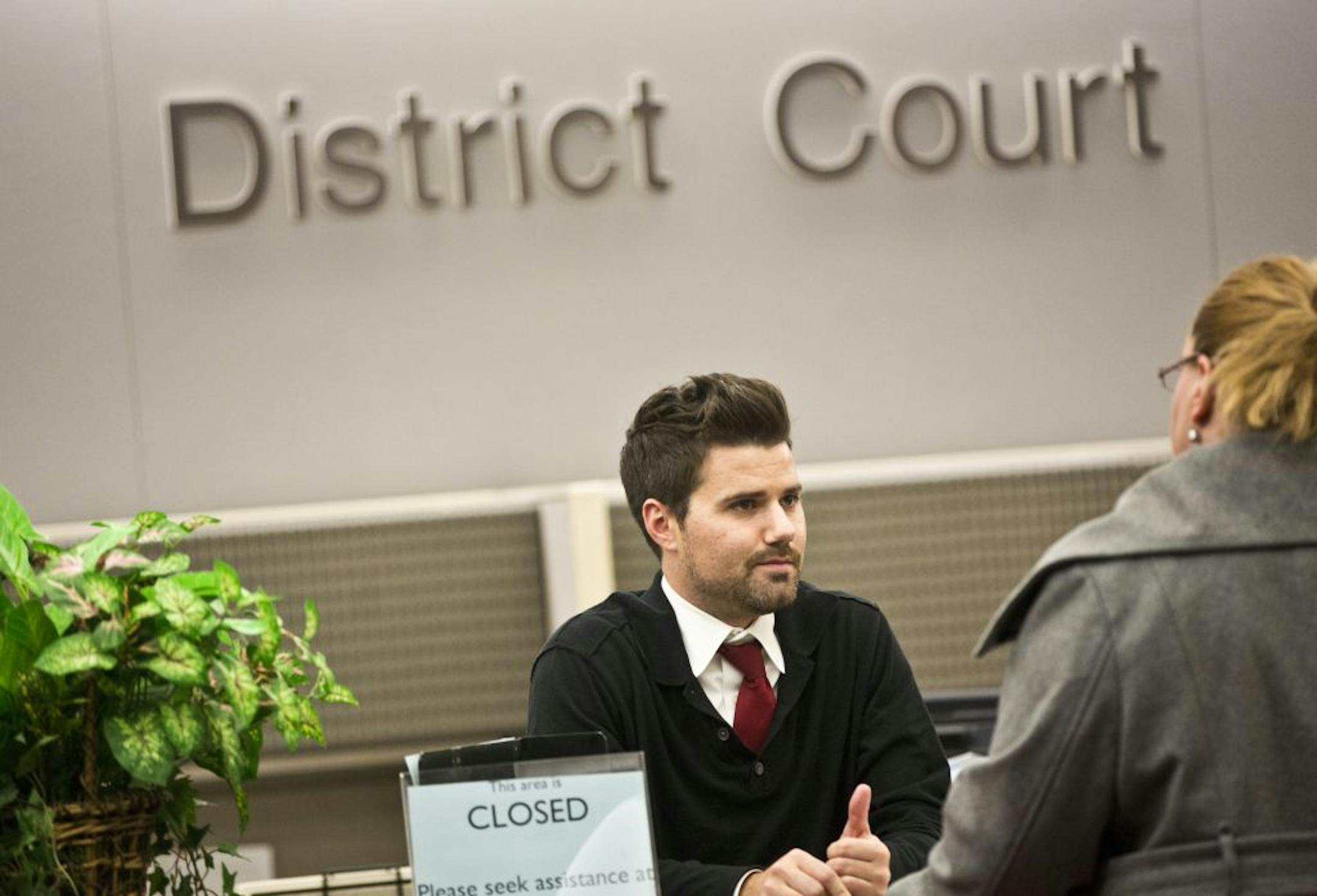 Court operations supervisor Aaron Williamson assisted a woman at the District Court desk at the Hennepin County Government Center in Minneapolis.