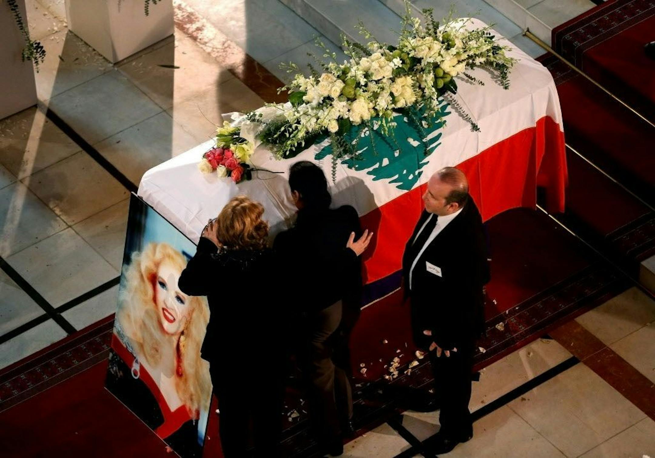 Relatives of Lebanese singer and actress Sabah, an icon of Arab music, mourn on her coffin during her funeral procession, at the St. George Cathedral in downtown Beirut, Lebanon, Sunday, Nov. 30, 2014. The daylong proceedings took on a festive air the crowds celebrated the taboo-breaking six-decade career of Sabah, who died Wednesday at the age of 87. A military brass band played in the street outside St. George Cathedral, where fans clapped and sang their favorite Sabah songs.