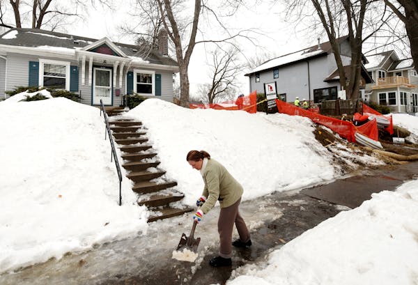 Sharon Potter of Minneapolis shovels her walkway as construction has started on a teardown next to her home on the 5100 block of York.