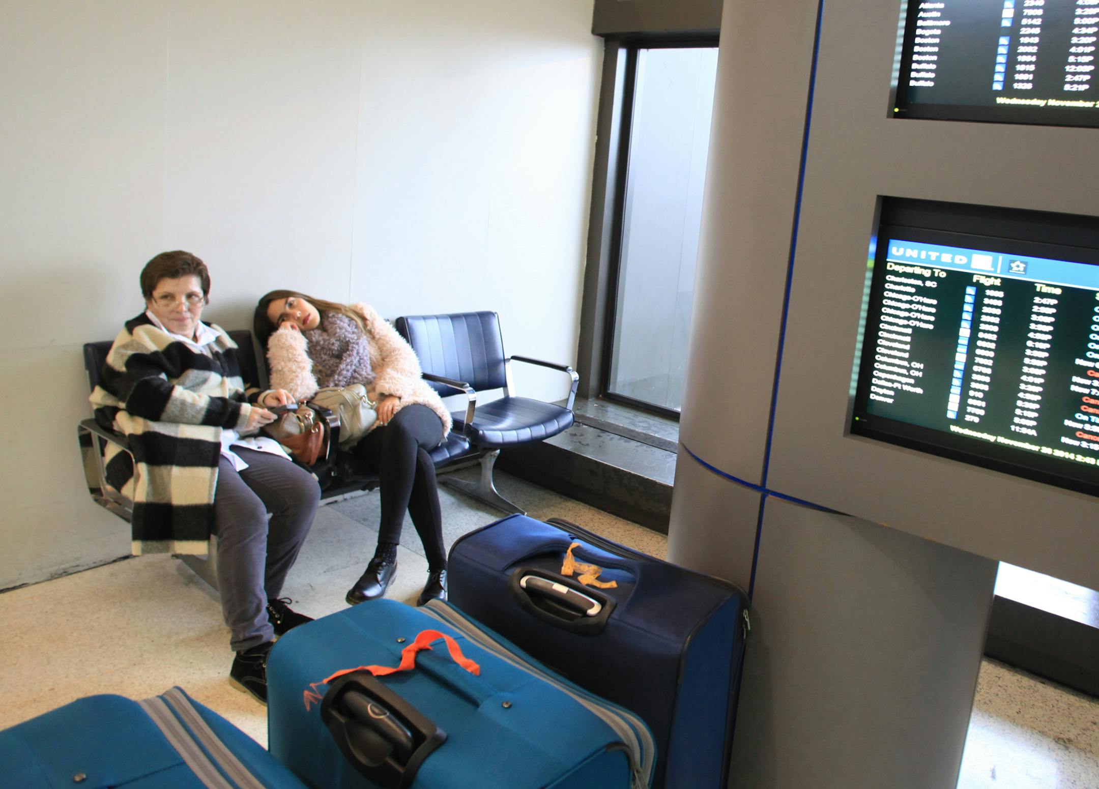 Pia Kiguelman of Wayne, N.J., with her niece Claudia Carvajal, of Bogota, Colombia, waits for their flight to Bogota that was delayed for an hour because of wintry weather, Wednesday, Nov. 26, 2014, at Newark Liberty International Airport in Newark, N.J. (AP Photo/Northjersey.com Chris Pedota)