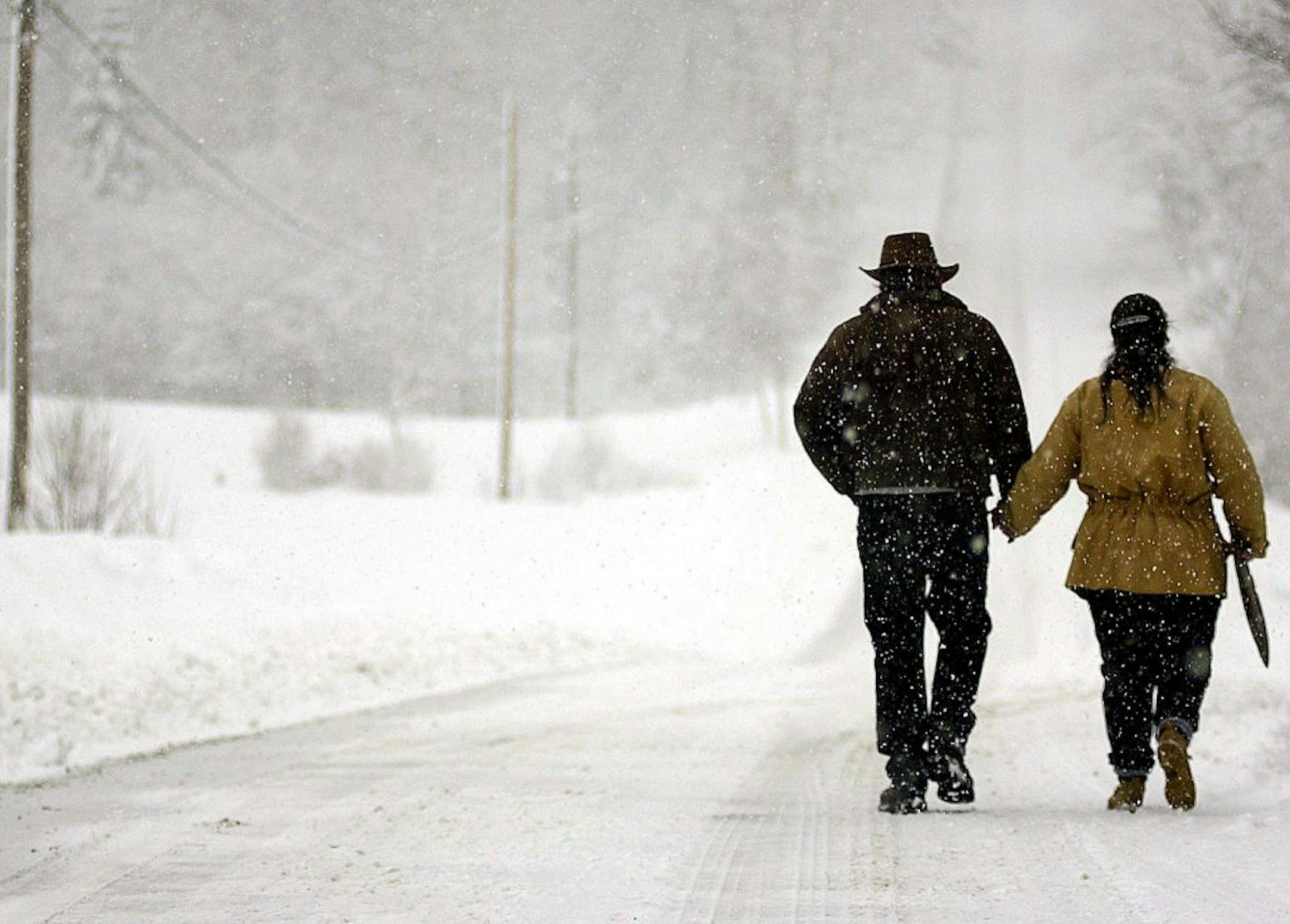 Larry and Linda Faillace holds hands as they take a long cold walk home through a heavy morning snow 22 March 2001 on Roxbury Gap Road in East Warren, Vermont, after speaking with reporters and stating that they believe their 126 imported sheep are going to be seized within the next 48 hours. The USDA seized 255 sheep from a farm in neighboring Greensboro, Vermont, suspected of containing a strain of mad cow disease 21 March 2001. AFP PHOTO/Steven E. FRISCHLING