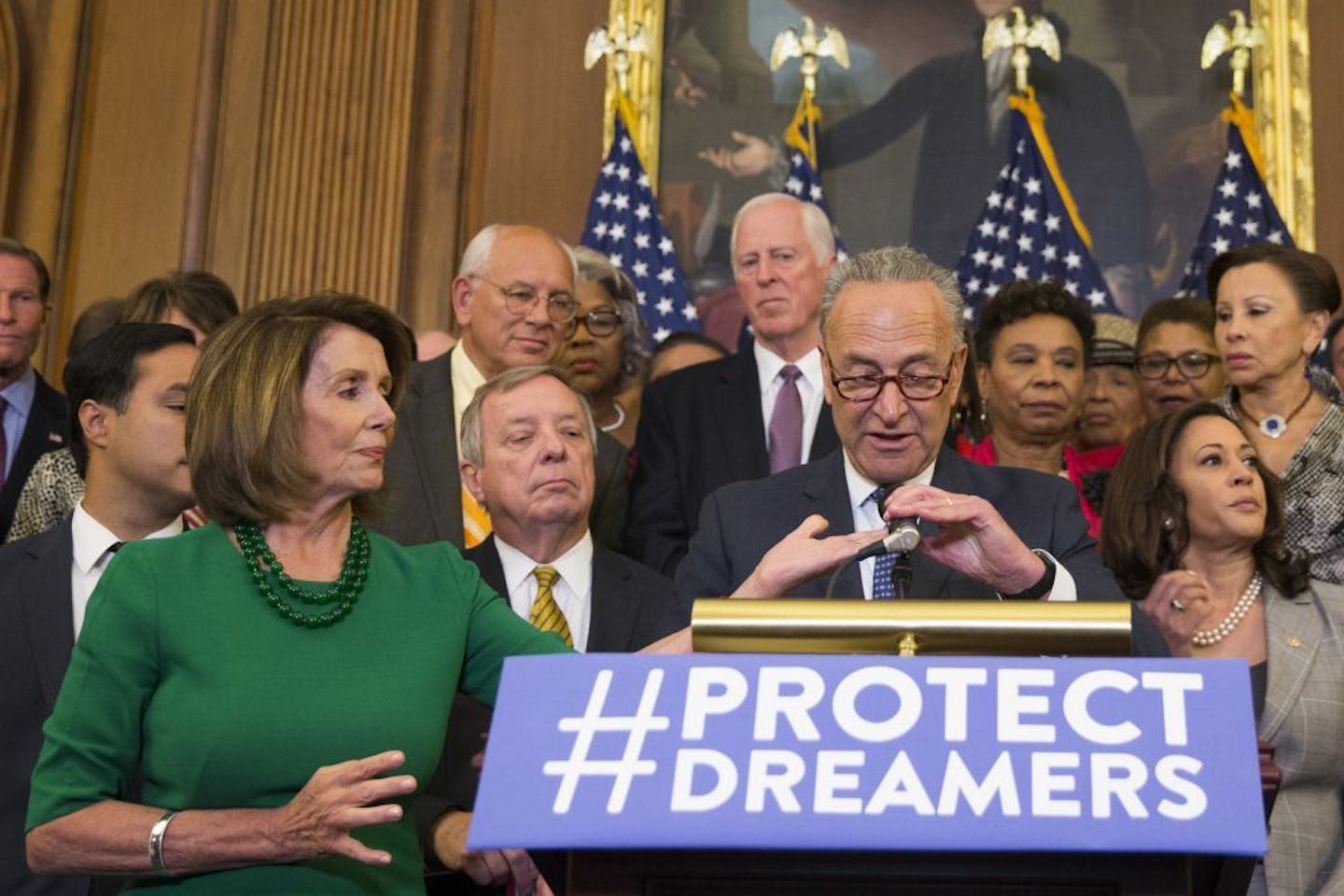 FILE-- House Minority Leader Nancy Pelosi (D-Calif.) adjusts a microphone for Senate Minority Leader Chuck Schumer (D-N.Y.) as he spoke on the Deferred Action for Childhood Arrivals program, on Capitol Hill in Washington, Sept. 6, 2017. Trump will dine at the White House Sept. 13 with Schumer and Pelosi, pursuing a bipartisan patina as he heads into the fall legislative season with little to show for his first year in office.