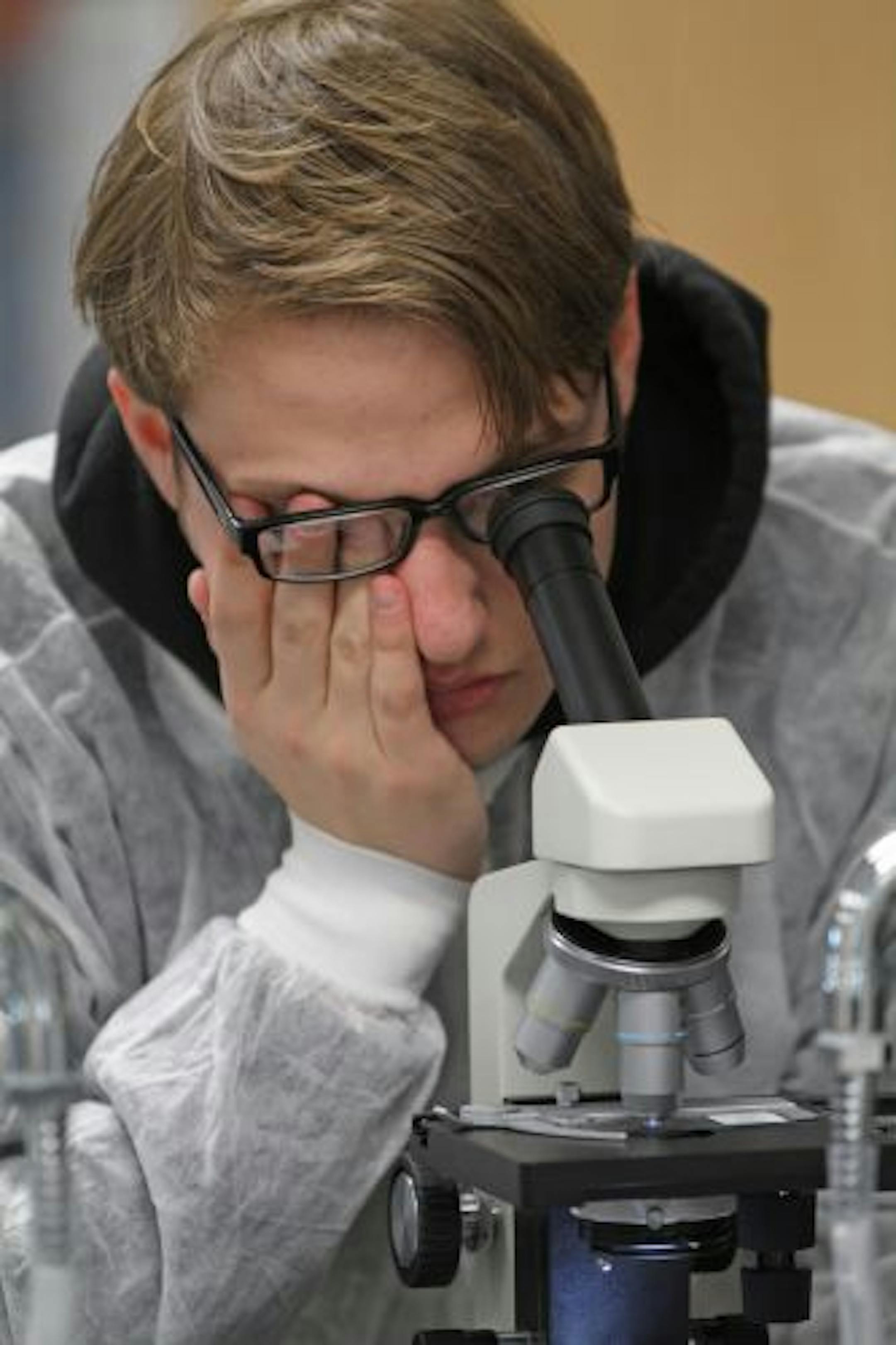 (left to right) East Ridge High School student Jack Lambert covered his one eye, as he used a microscope to look at slides of sickle cell anemia and healthy cells during Nancy Berg's Principals fo Bio-Medical Science class. The course, one of the first in the nation, offers students the opportunity to learn about medicine and is funded by 3M.