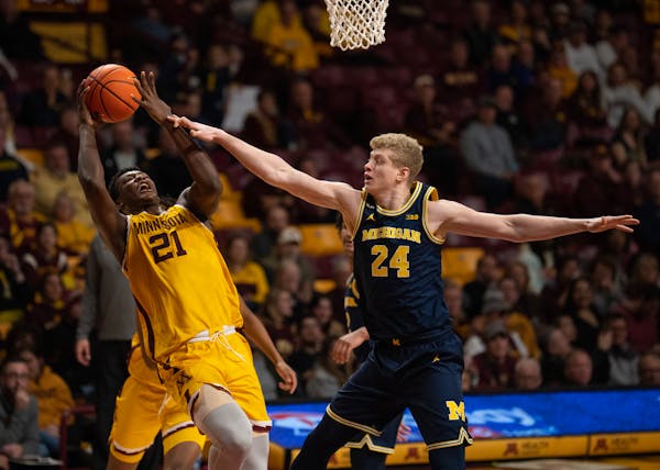 Minnesota Gophers forward Pharrel Payne (21) tried to get a shot off as he was fouled by Michigan Wolverines forward Youssef Khayat (24) during the se