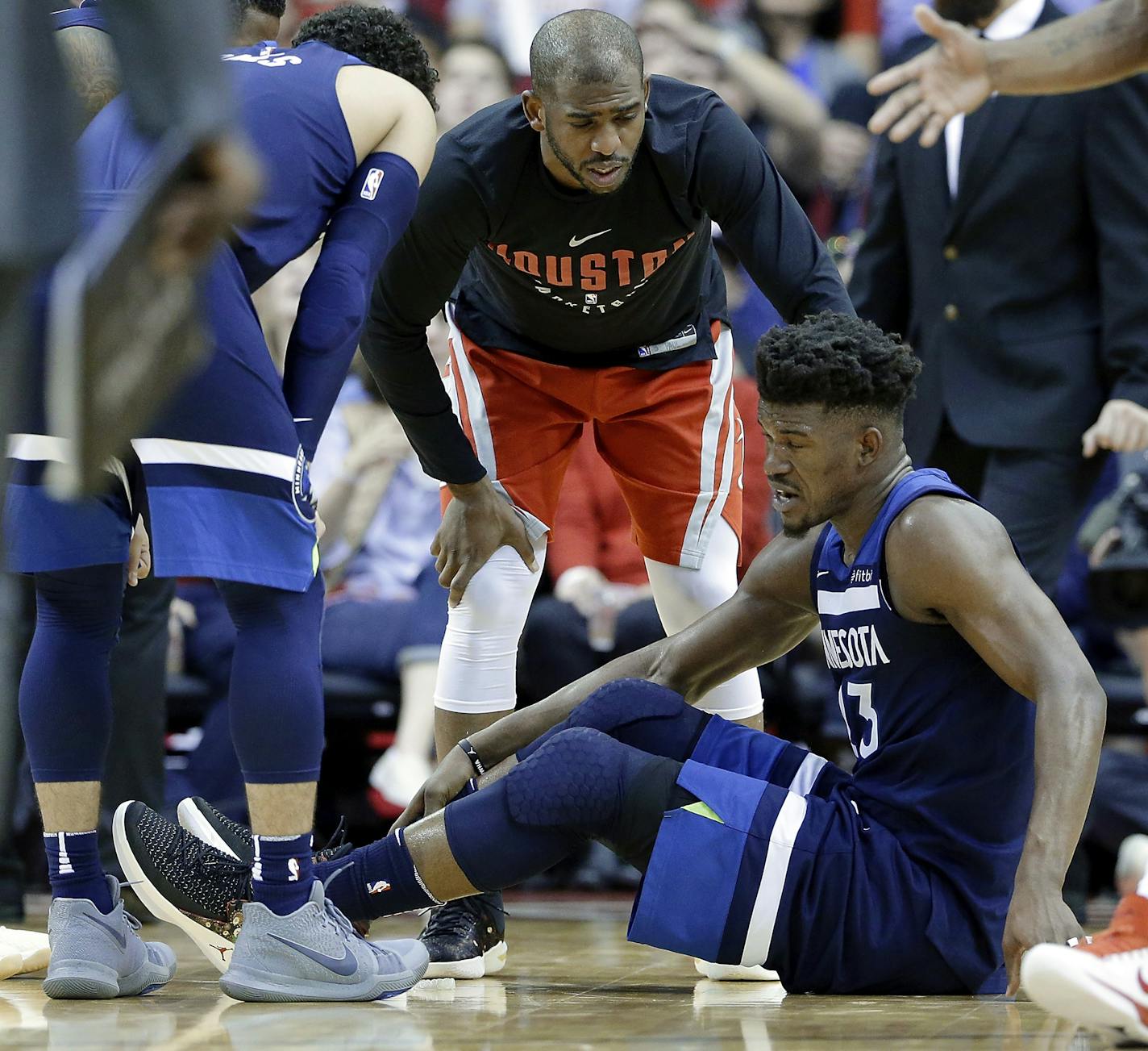 Minnesota Timberwolves guard Jimmy Butler (23) reacts to a knee injury on the court as Houston Rockets guard Chris Paul (3) hovers over him during the second half of an NBA basketball game Friday, Feb. 23, 2018, in Houston. (AP Photo/Michael Wyke)