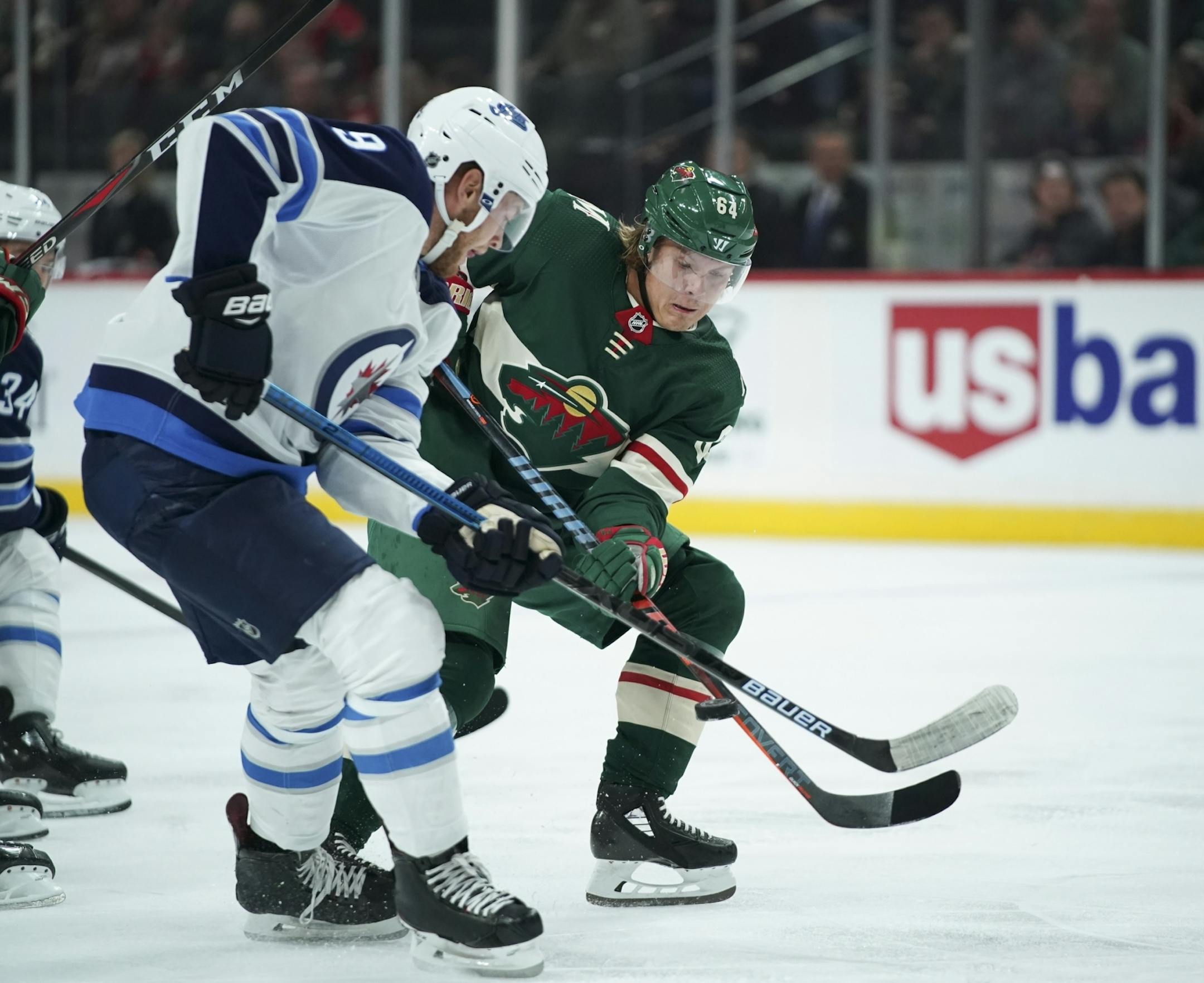 Minnesota Wild right wing Mikael Granlund (64) tried to deflect the puck while defended by Winnipeg Jets center Andrew Copp (9) in the first period.