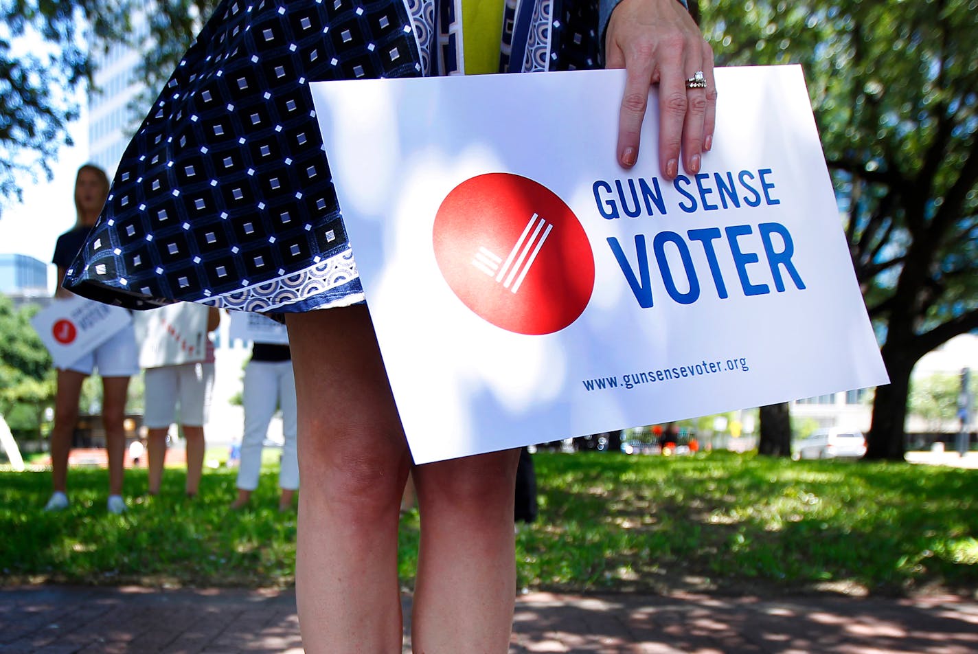 In Dallas, a woman carries a sign demanding action for gun sense in Target stores. She and others were protesting outside Target Corporation's annual shareholder meeting.