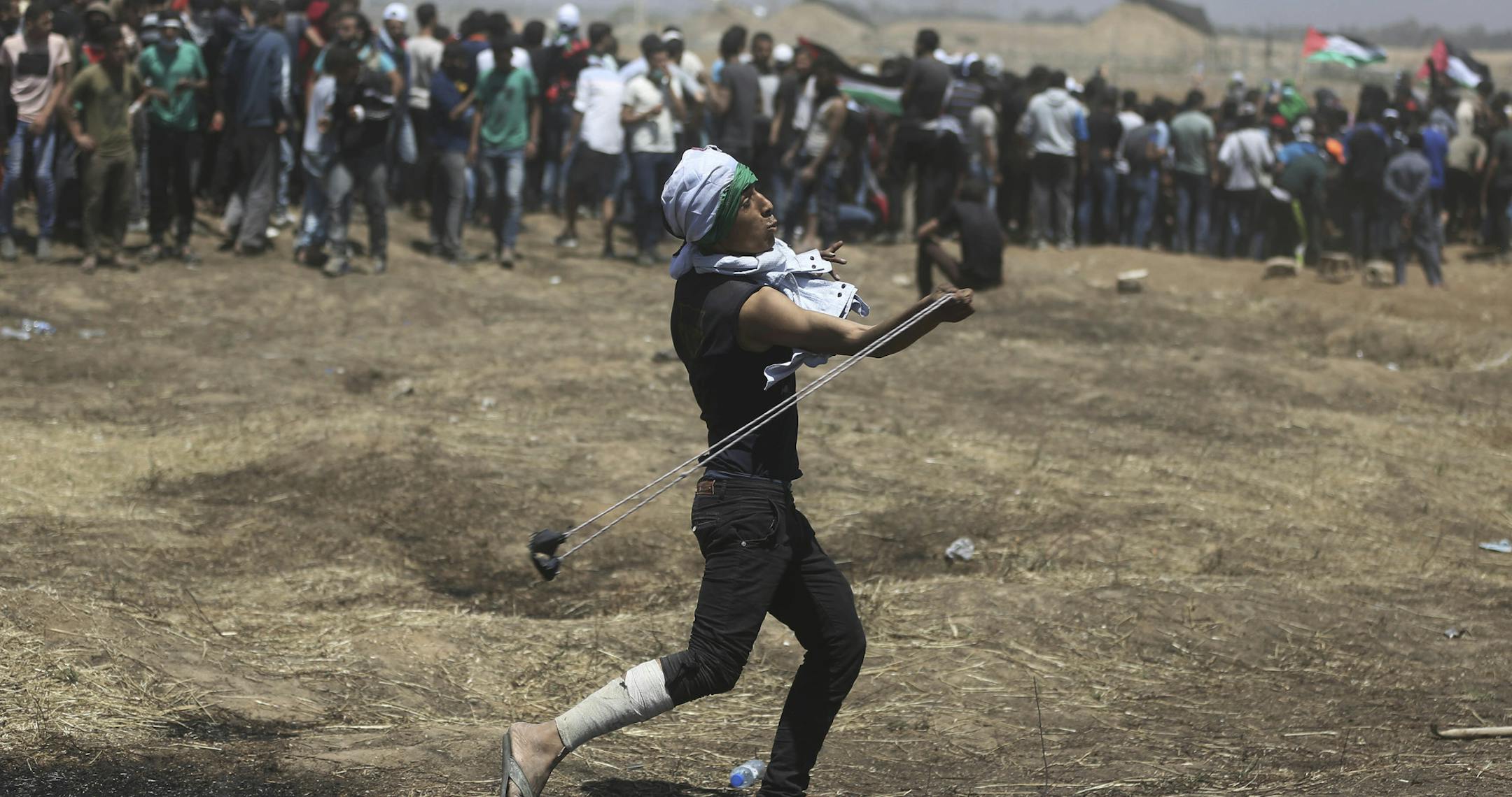 A Palestinian protester hurls stones at Israeli troops during a protest at the Gaza Strip's border with Israel, Monday, May 14, 2018. Thousands of Palestinians are protesting near Gaza's border with Israel, as Israel prepared for the festive inauguration of a new U.S. Embassy in contested Jerusalem. (AP Photo/Khalil Hamra)