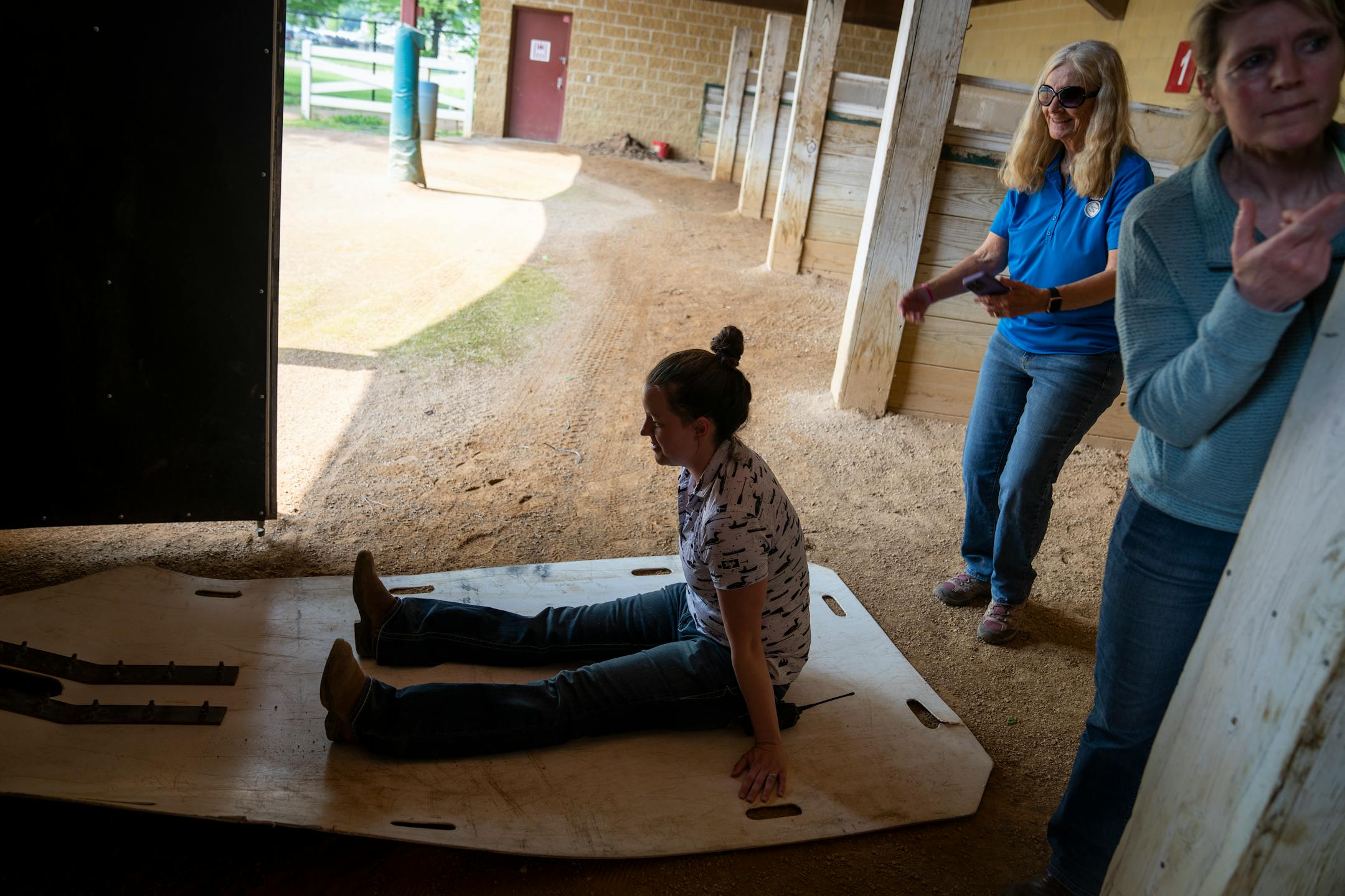 Dr. Rebecca Butler, from left, sits as the stand-in for a horse as she is pulled into an equine ambulance during a Horse Racing Integrity and Safety Authority (HISA)-mandated preseason drills run by Dr. Lynn Hovda and assisted by Dr. Christy Klatt at Canterbury Park in Shakopee, Minn.