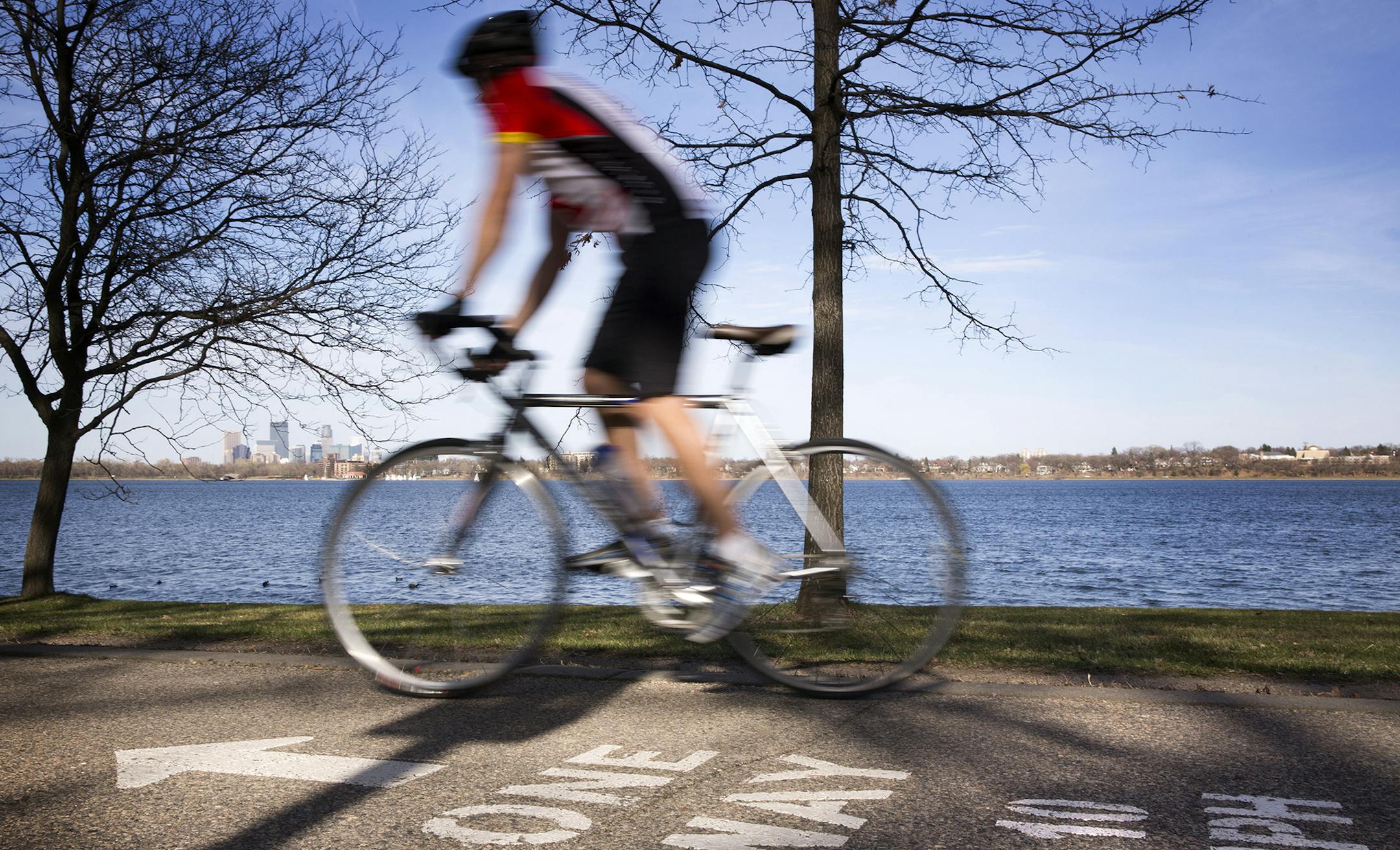 A bicyclist rides along the bike path around Lake Calhoun in Minneapolis on Wednesday, April 15, 2015. ] LEILA NAVIDI leila.navidi@startribune.com / BACKGROUND INFORMATION: City park officials are debating doing away with the bicycle speed limit of 10 mph, saying they are not enforceable. ORG XMIT: MIN1504151734402075