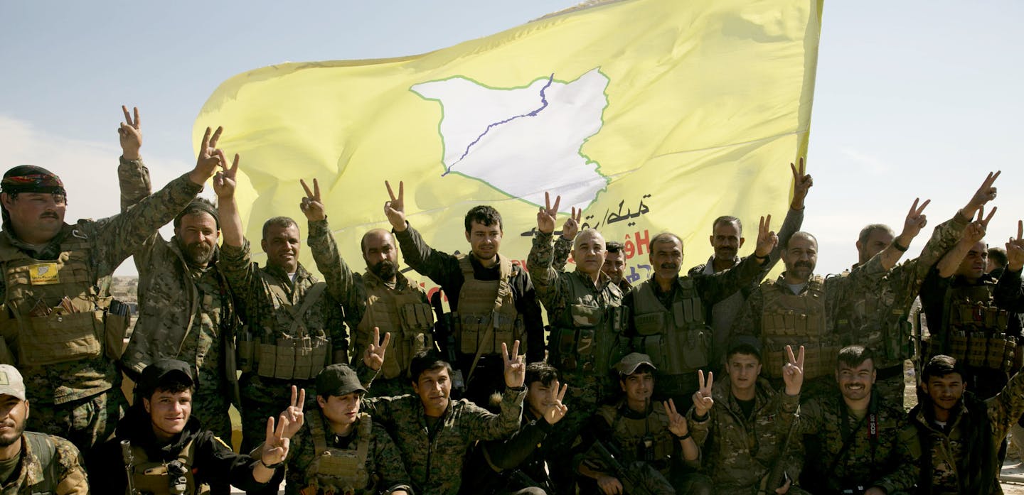 U.S.-backed Syrian Democratic Forces (SDF) fighters pose for a photo on a rooftop overlooking Baghouz, Syria, after the SDF declared the area free of Islamic State militants after months of fighting on Saturday, March 23, 2019. The elimination of the last Islamic State stronghold in Baghouz brings to a close a grueling final battle that stretched across several weeks and saw thousands of people flee the territory and surrender in desperation, and hundreds killed. (AP Photo/Maya Alleruzzo)