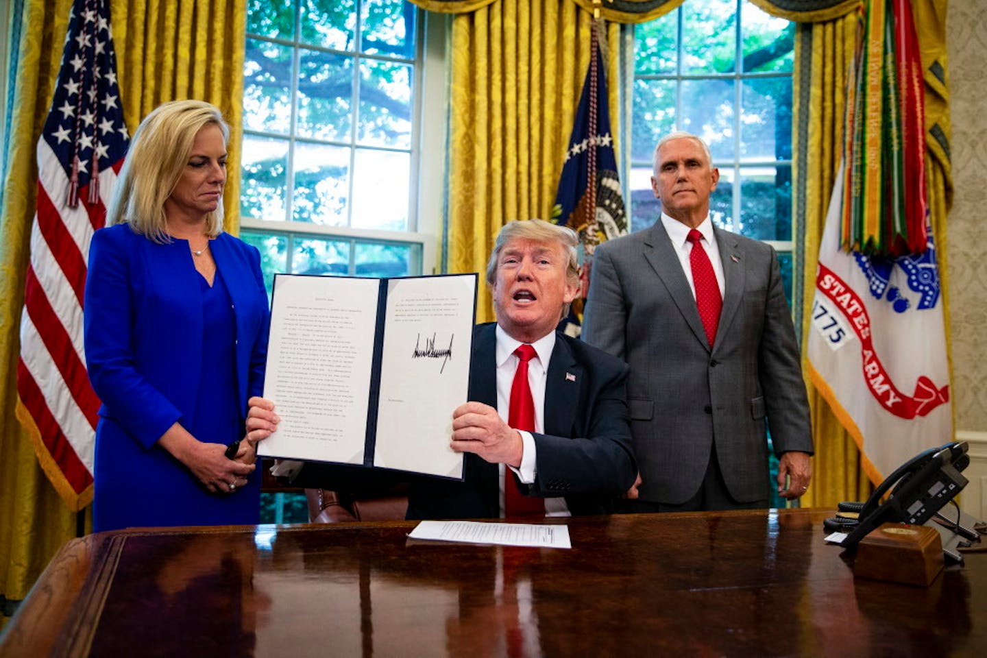 President Donald Trump, with Homeland Security Secretary Kristjen Nielsen and Vice President Mike Pence, signs an executive order Wednesday on immigrant family separations. The order ends the separation of families at the border by indefinitely detaining parents and children together, according to a person familiar with the White House plans.