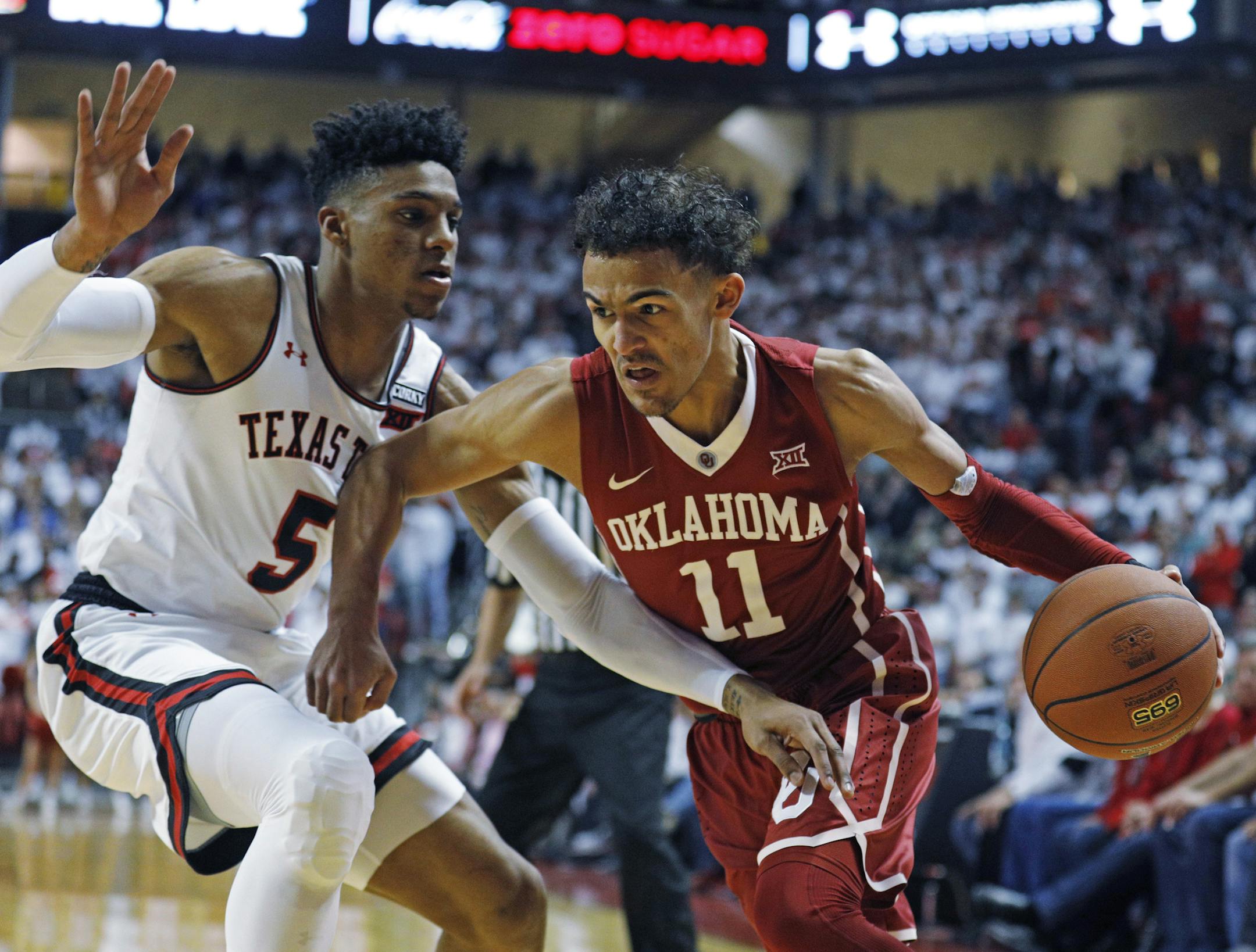 Oklahoma's Trae Young (11) dribbles the ball around Texas Tech's Justin Gray (5) during an NCAA college basketball game Tuesday, Feb. 13, 2018, in Lubbock, Texas. (AP Photo/Brad Tollefson)