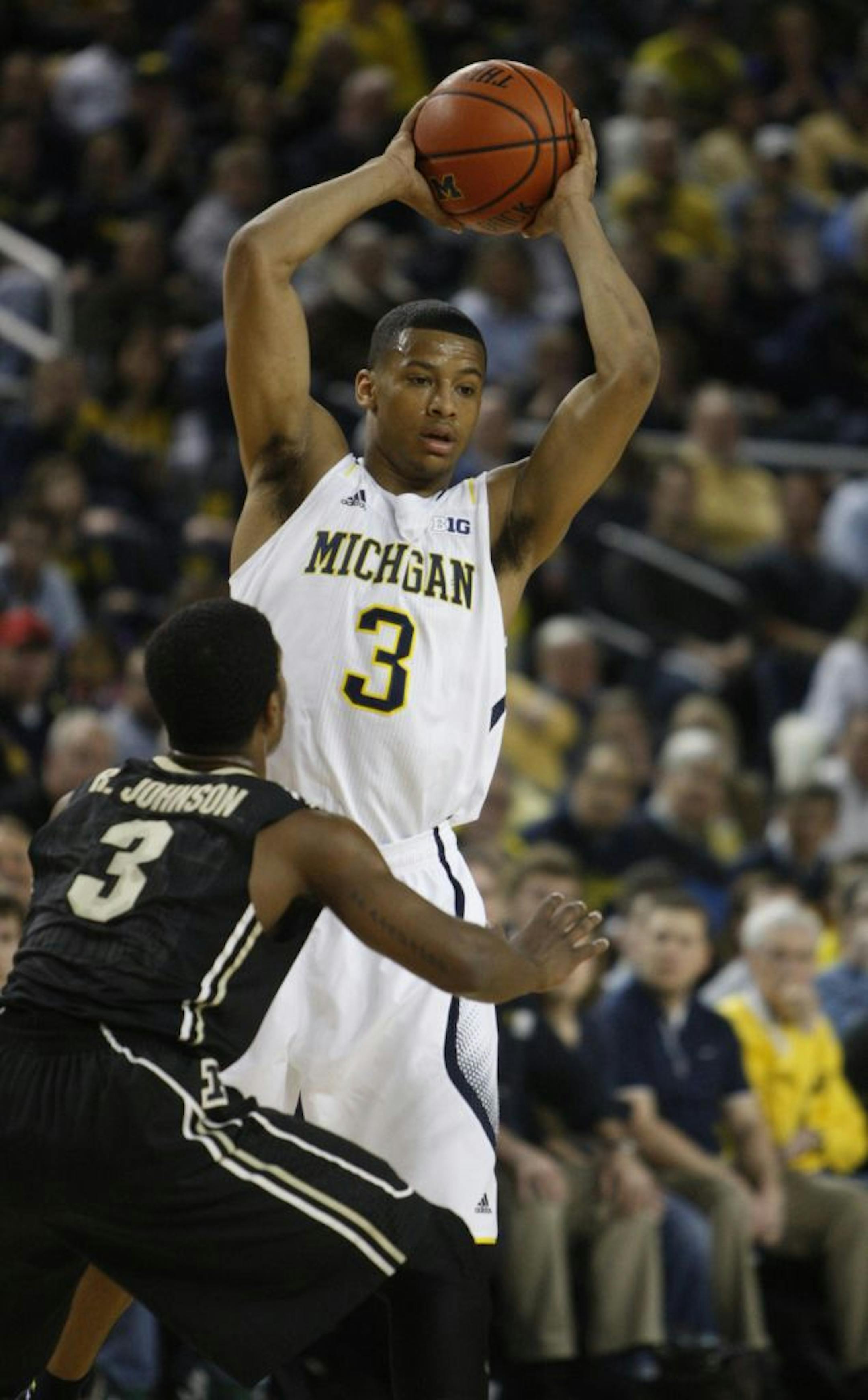 Michigan's Trey Burke passes away from pressure by Purdue's Ronnie Johnson during first-half action on Thursday, January 24, 2013, at Crisler Arena in Ann Arbor, Michigan. The host Wolverines won, 68-53.