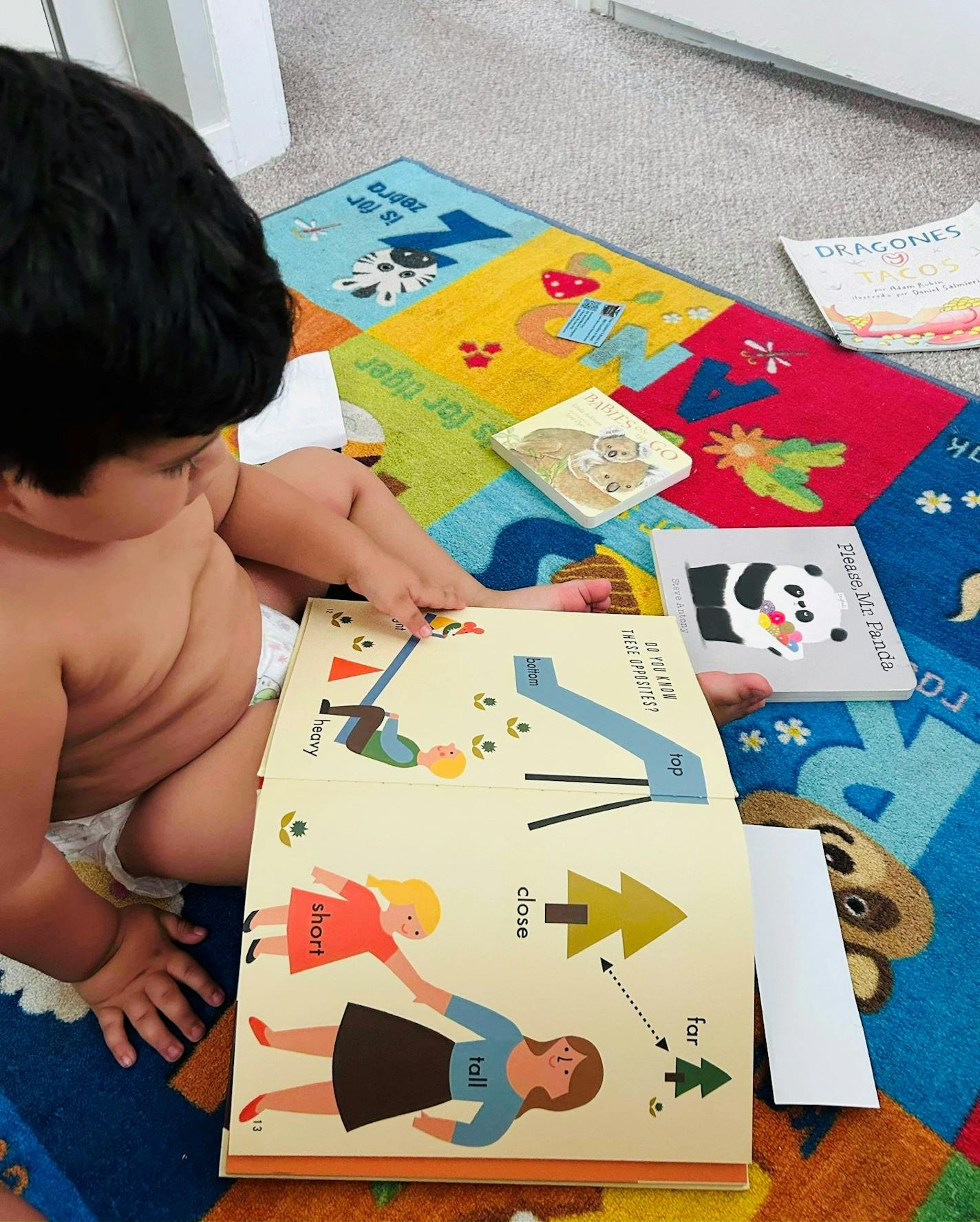 photo of baby reading a book on a blanket