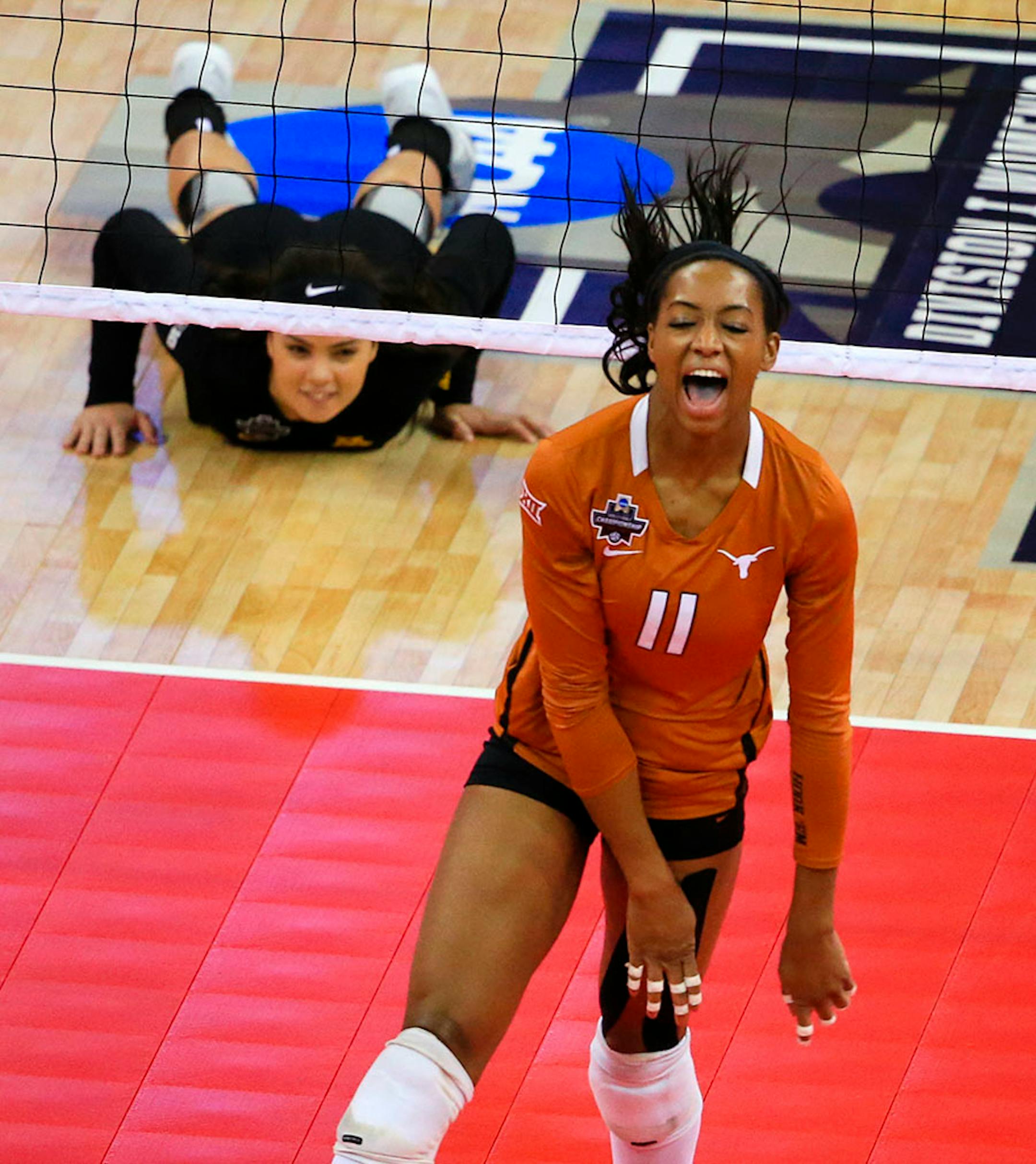 Minnesota's Dalianliz Rosado (17) lies on the court as Texas' Chiaka Ogbogu (11) celebrates a kill during an NCAA women's volleyball tournament semifinal in Omaha, Neb., Thursday, Dec. 17, 2015.