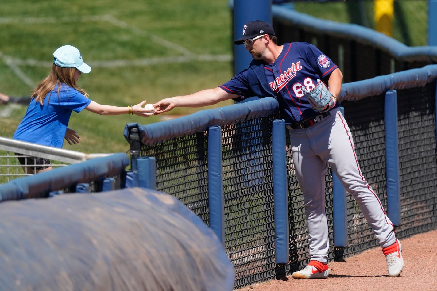 Minnesota Twins relief pitcher Randy Dobnak (68) hands a baseball to a young fan before a spring training baseball game against the Tampa Bay Rays Saturday, March 13, 2021, in Port Charlotte, Fla.. (AP Photo/John Bazemore)