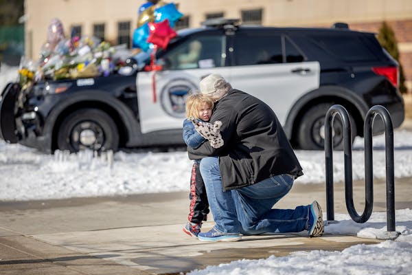 Wes Haynes hugged his son Eddie-Ray Haynes after placing flowers on three memorials in front of the Burnsville Police Department in Burnsville on Mond
