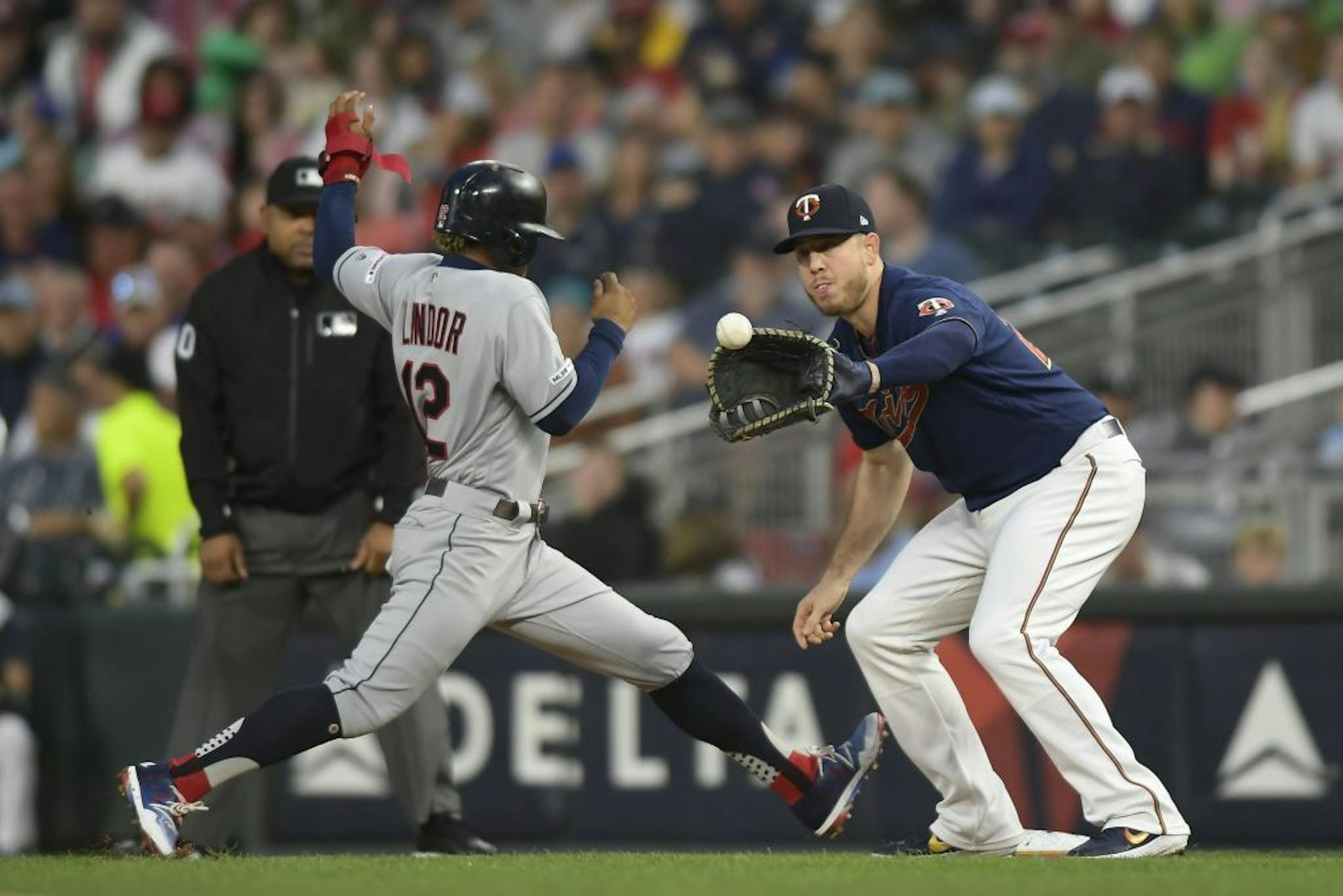 Cleveland Indians shortstop Francisco Lindor (12) safely tagged back to first as Minnesota Twins first baseman C.J. Cron (24) caught a ball thrown by starting pitcher Jake Odorizzi (12) in the top of the first inning.