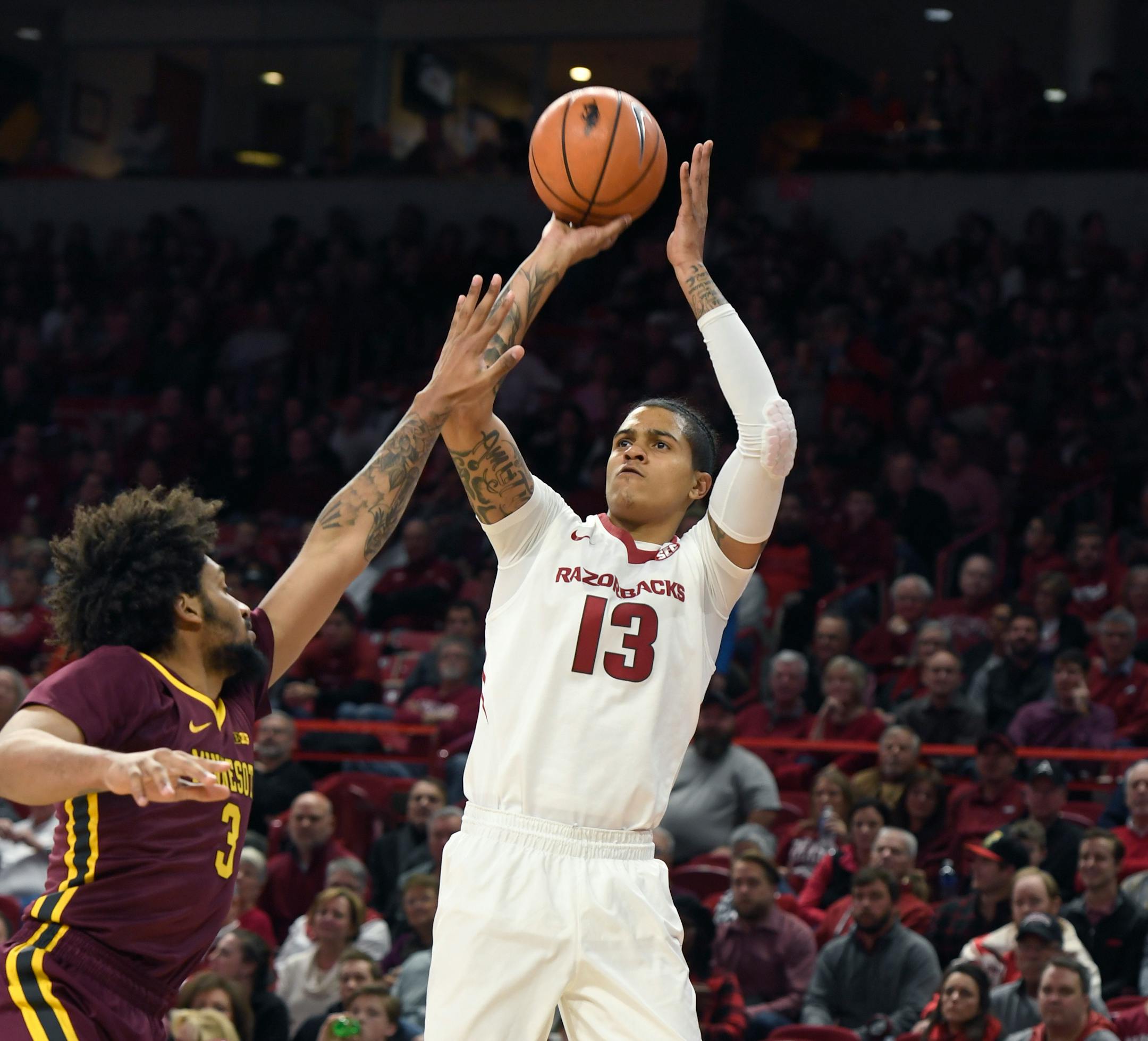 Arkansas forward Dustin Thomas pulls up for a jump shot over Minnesota defender Jordan Murphy in the first half of an NCAA college basketball game Friday, Dec. 9, 2017 in Fayetteville, Ark. (AP Photo/Michael Woods)