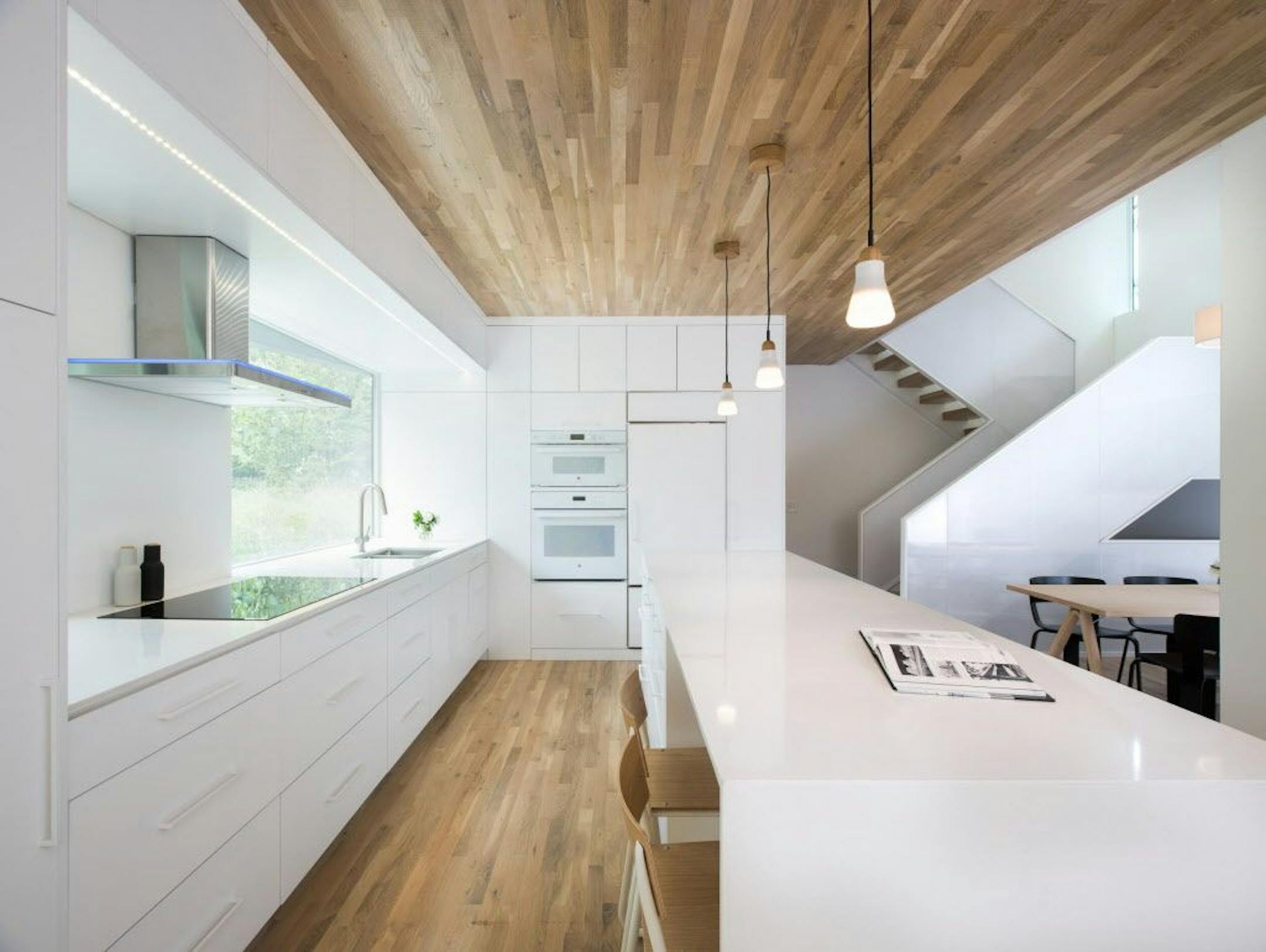 White oak ceiling and flooring warm up the all-white kitchen.