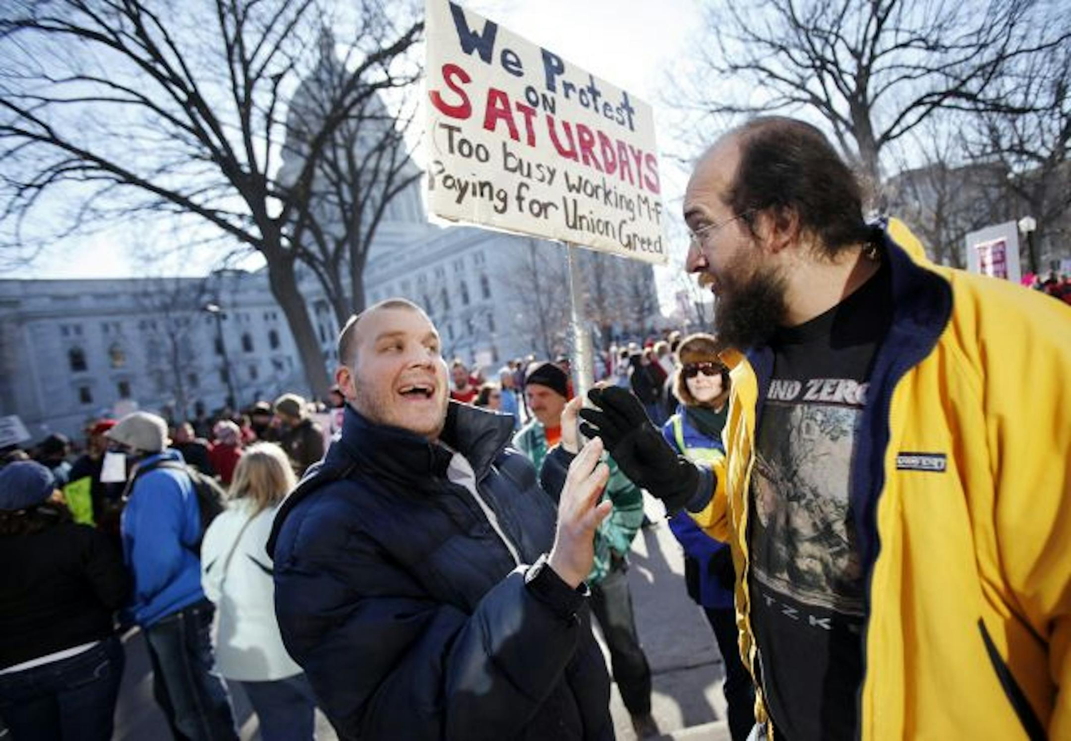 Tom Braun and Nathaniel Raghez, both of Milwaukee, debate opposite sides of Wisconsin's proposed budget repair bill near the state Capitol in Madison, Wis., Saturday, Feb. 19, 2011. A few dozen police officers stood between supporters of Republican Gov. Scott Walker on the muddy east lawn of the Capitol and the much larger group of pro-labor demonstrators who surrounded them. The protest was peaceful as both sides exchanged chants of �Pass the bill! Pass the bill!� and �Kill the bill! Kill the b