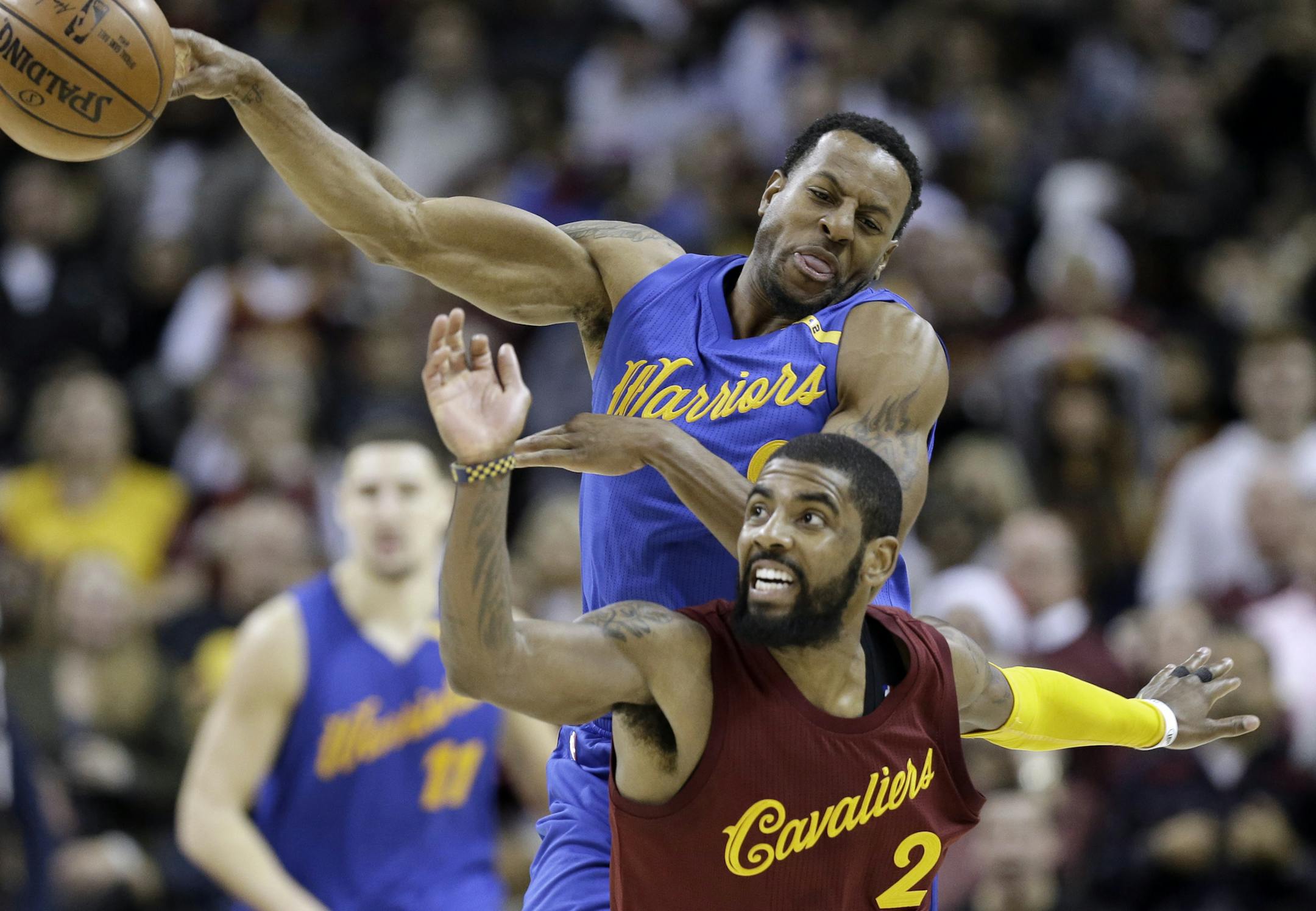 Cleveland Cavaliers' Kyrie Irving (2) and Golden State Warriors' Andre Iguodala (9) battle for a loose ball in the second half of an NBA basketball game, Sunday, Dec. 25, 2016, in Cleveland. The Cavaliers won 109-108. (AP Photo/Tony Dejak)
