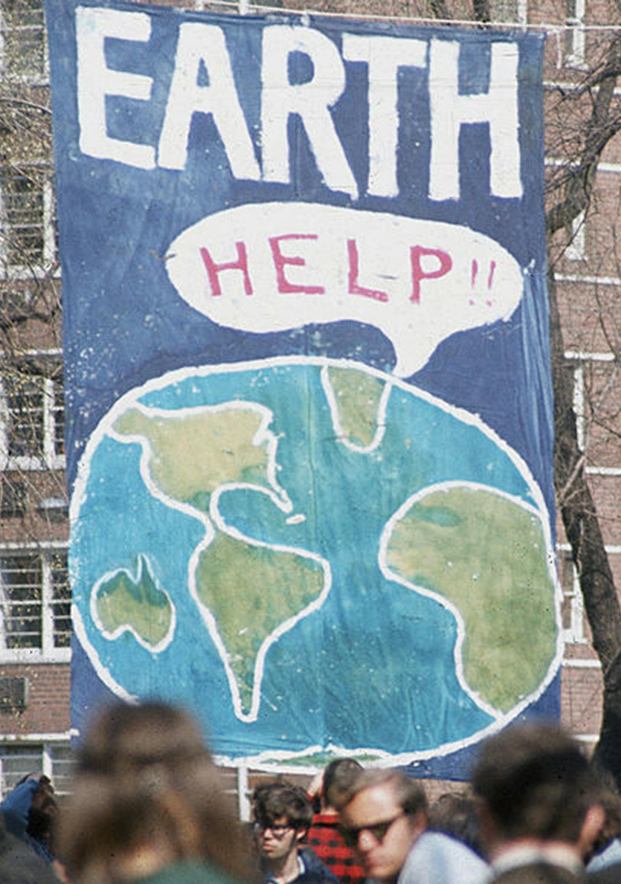 A crowd of people gather near a large poster that shows a speach bubble from planet Earth that reads 'Help!!,' on the first Earth Day conservation awareness celebration, New York, New York, April 22, 1970. (Hulton Archive/Getty Images/TNS) ORG XMIT: 1635790
