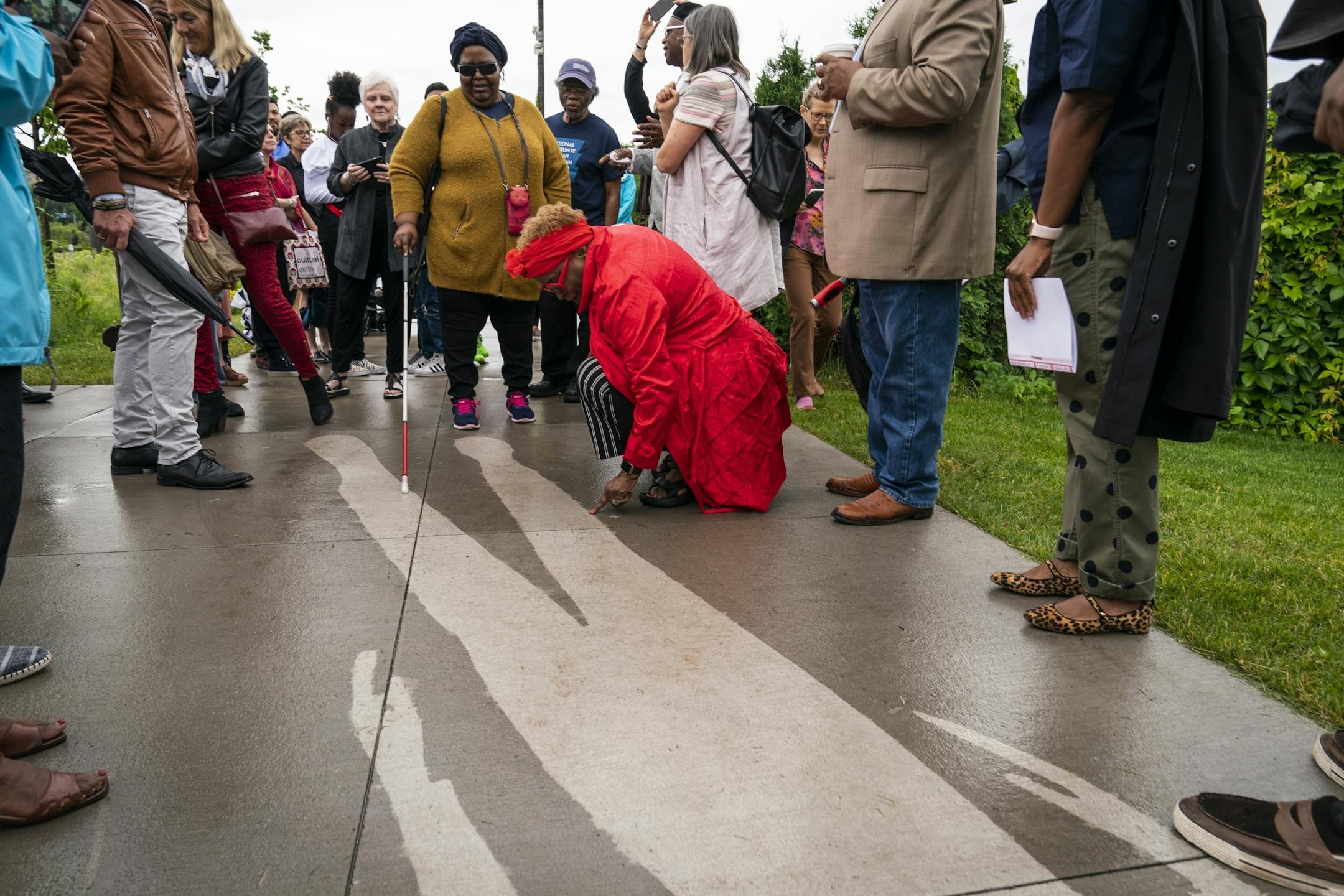 People explore the piece "Kirk Washington, Jr." which only reveals itself when it rains, from the series "Shadows at the Crossroads" during the public unveiling.
