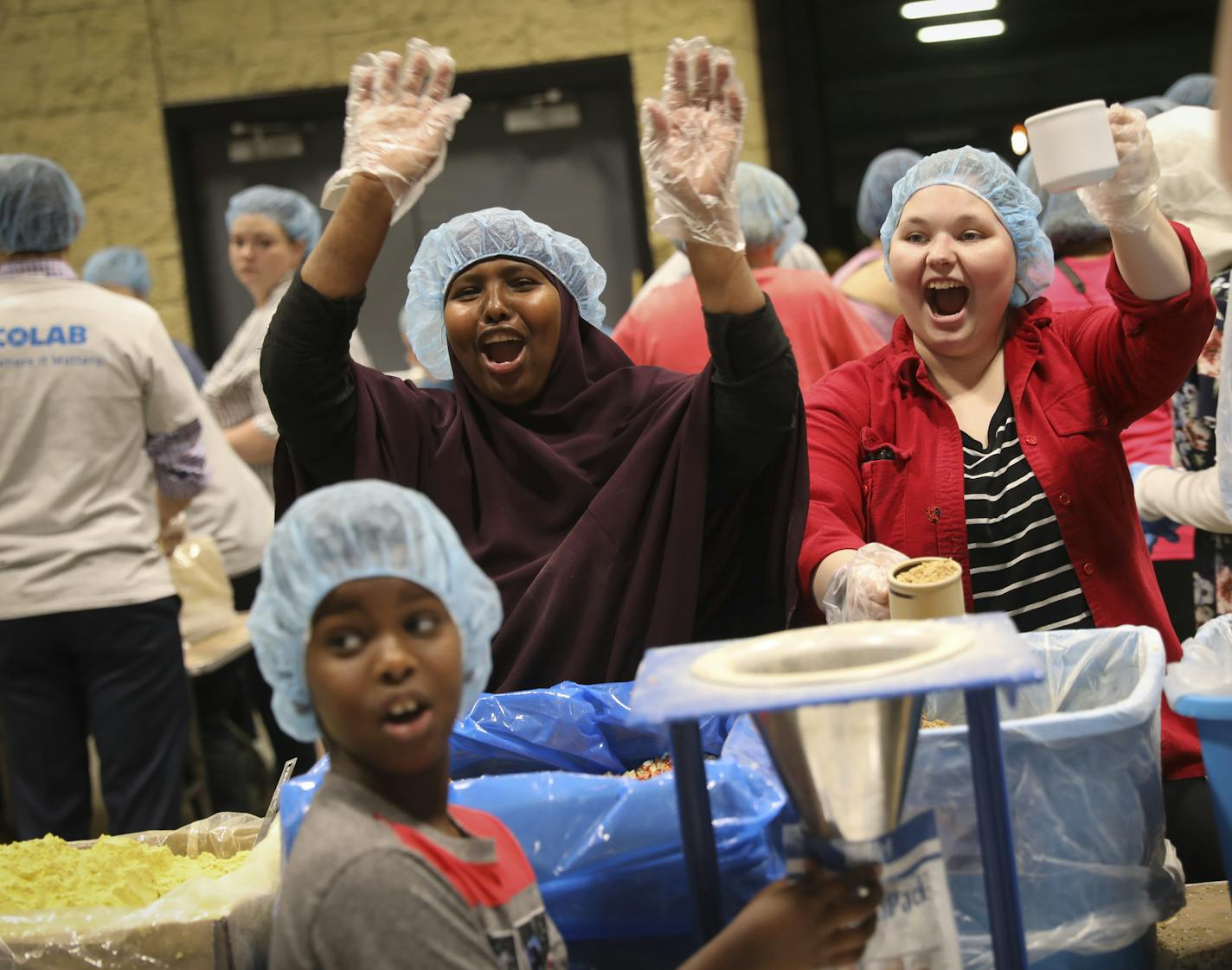 From right to left, Lexy Redenbaugh, Nuurto Hirsi and her son Yusuf Hirsi cheered with their table mates after completely filling a box during one of three packing sessions for Feed My Starving Children organized to help Somalia, at the RiverCentre in St. Paul, Minn., on Monday, June 5, 2017. Feed My Starving Children, a Minnesota-based nonprofit, rallied volunteers this weekend and today to raise funds to fight a looming famine in Somalia. This is the largest meal-packing event in the charity's