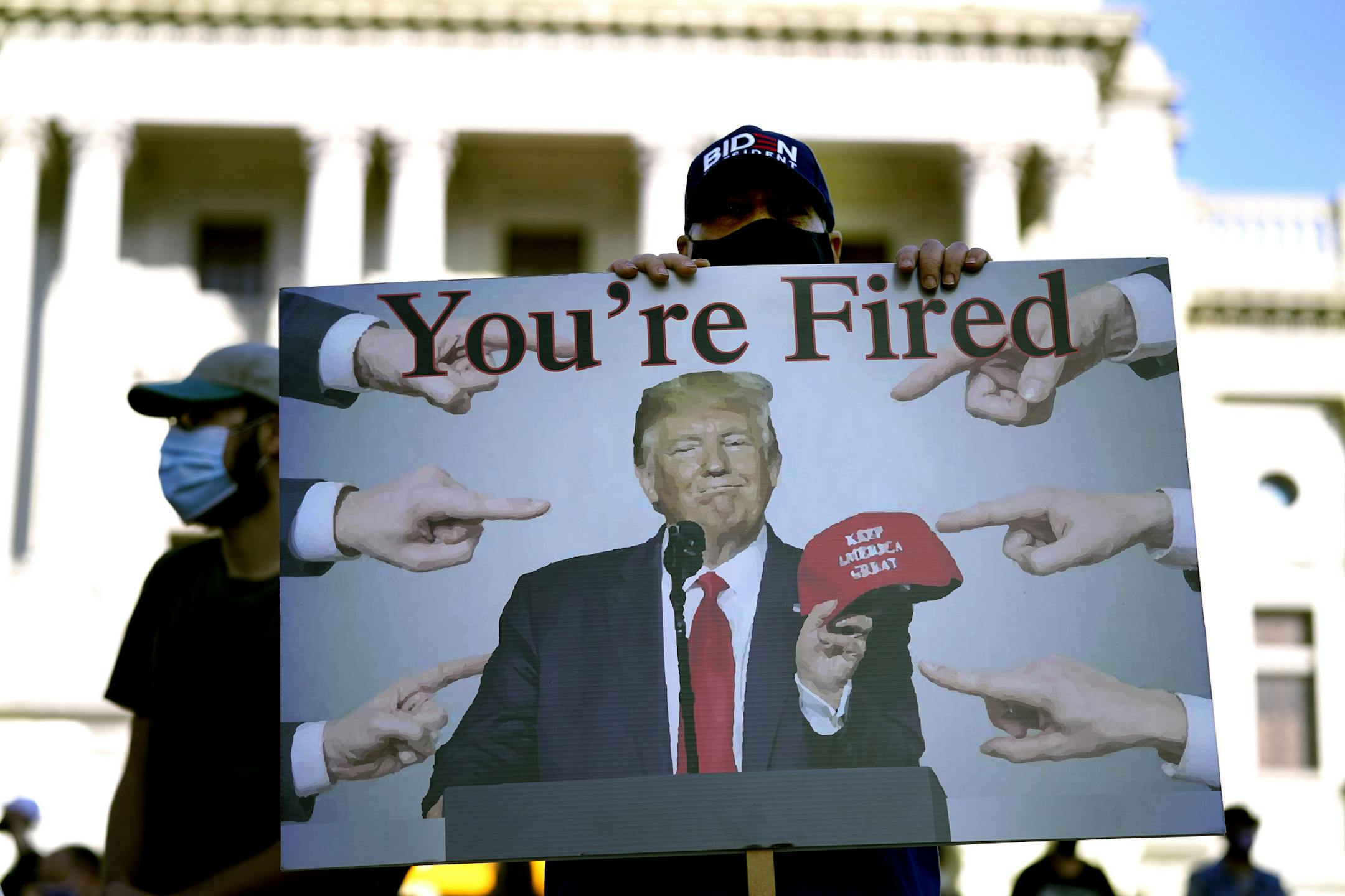 A supporter of President-elect Joe Biden holds a sign referring to President Donald Trump outside the Pennsylvania State Capitol, Saturday, Nov. 7, 2020, in Harrisburg, Pa., after Biden defeated Trump to become 46th president of the United States. (AP Photo/Julio Cortez)