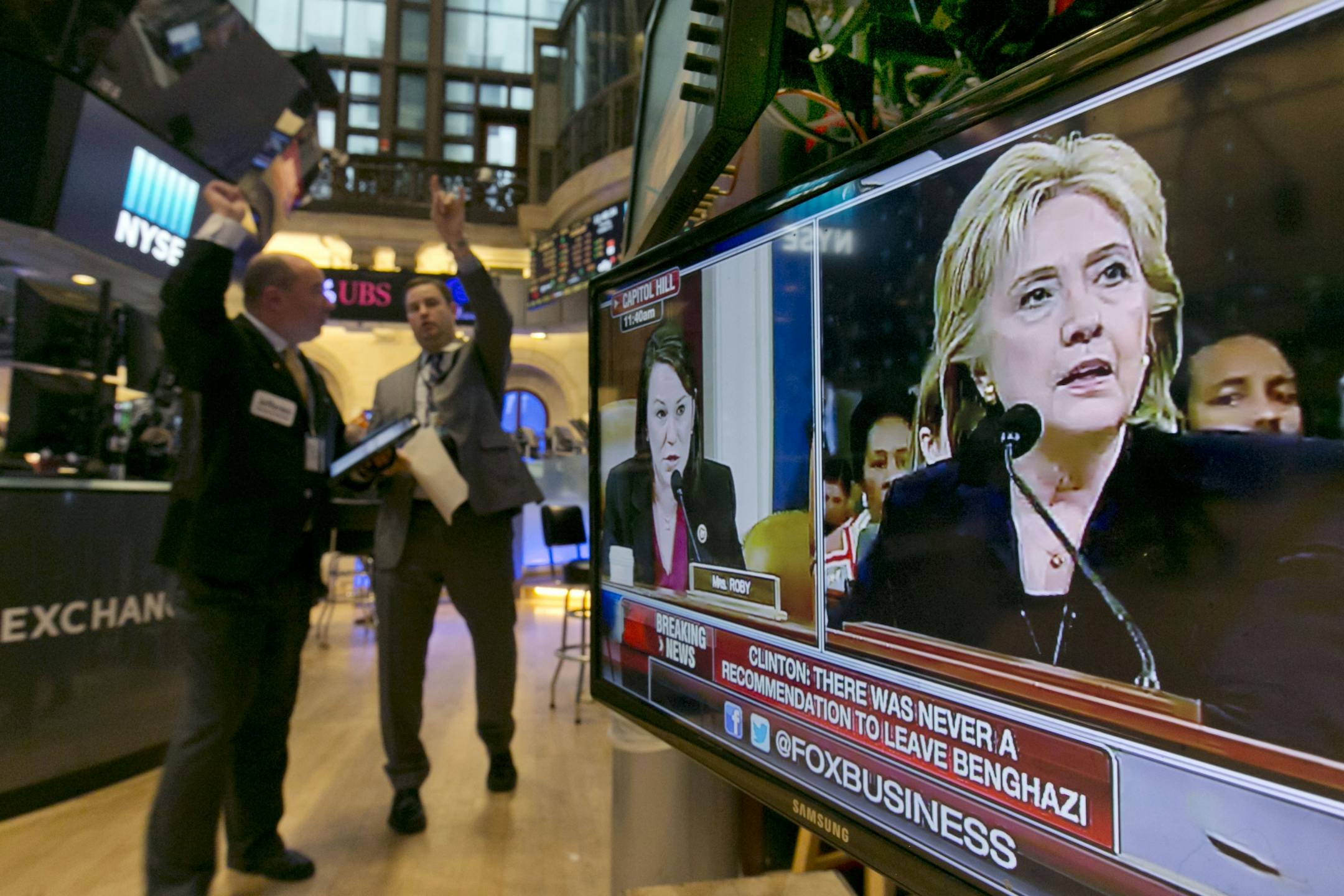 Hillary Rodham Clinton's testimony before a congressional committee appears on a television on the floor of the New York Stock Exchange, Thursday, Oct. 22, 2015. Clinton firmly defended her actions on Benghazi as she came face-to-face Thursday with the Republican-led special investigation of the 2012 attacks on a U.S. diplomatic mission in the Libyan city.