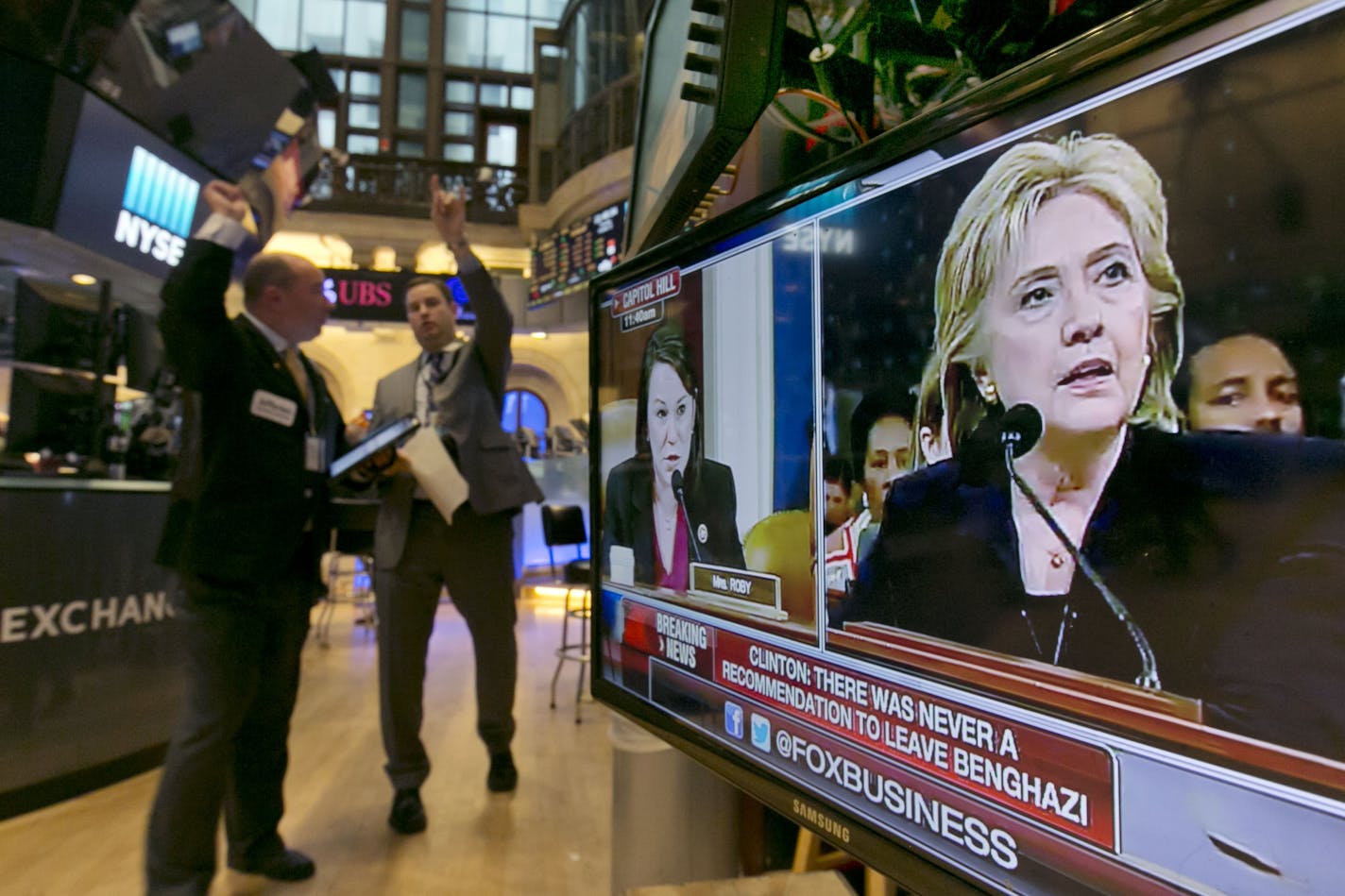 Hillary Rodham Clinton's testimony before a congressional committee appears on a television on the floor of the New York Stock Exchange, Thursday, Oct. 22, 2015. Clinton firmly defended her actions on Benghazi as she came face-to-face Thursday with the Republican-led special investigation of the 2012 attacks on a U.S. diplomatic mission in the Libyan city.