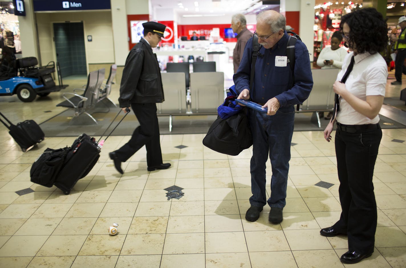 Geek Squad "covert agent" Lucinda Peery helped Bill English try out a Star Wars gadget at a pop-up Geek Squad counter before his flight on Monday, December 14, 2015, at Terminal 1 at the Minneapolis/St. Paul Airport in Bloomington, Minn. ] RENEE JONES SCHNEIDER &#x2022; reneejones@startribune.com