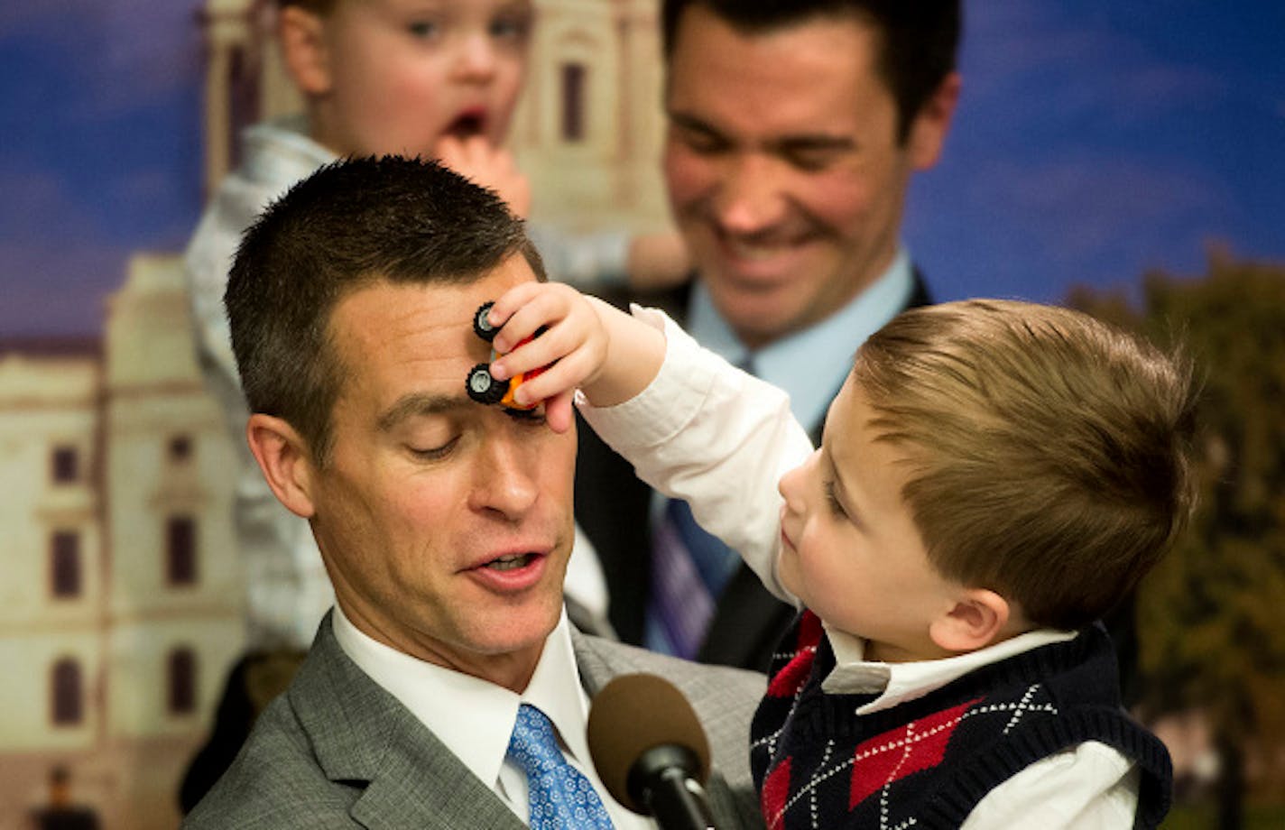 Dr. Paul Melchert got an unexpected car across the face from son Emmett while he spoke at the news conference.  Behind him is husband James Zimmerman with the couple's other son Gabriel.  Surrounded by same-sex couples and their children, Senator Scott Dibble and Rep. Karen Clark introduced their bill to legalize same-sex marriages in Minnesota. Wednesday, February 27, 2013.    ]   GLEN STUBBE * gstubbe@startribune.com