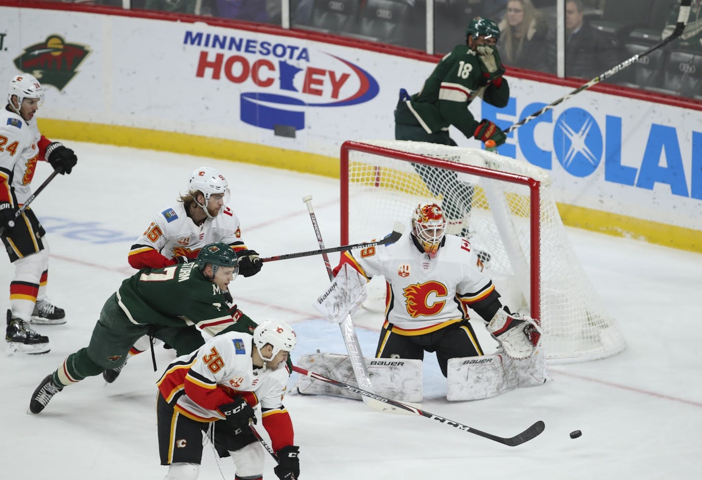 Minnesota Wild center Nico Sturm (7) reached in vain for a puck in the third period while in front of Calgary Flames goaltender Cam Talbot (39) with Flames defenseman Noah Hanifin