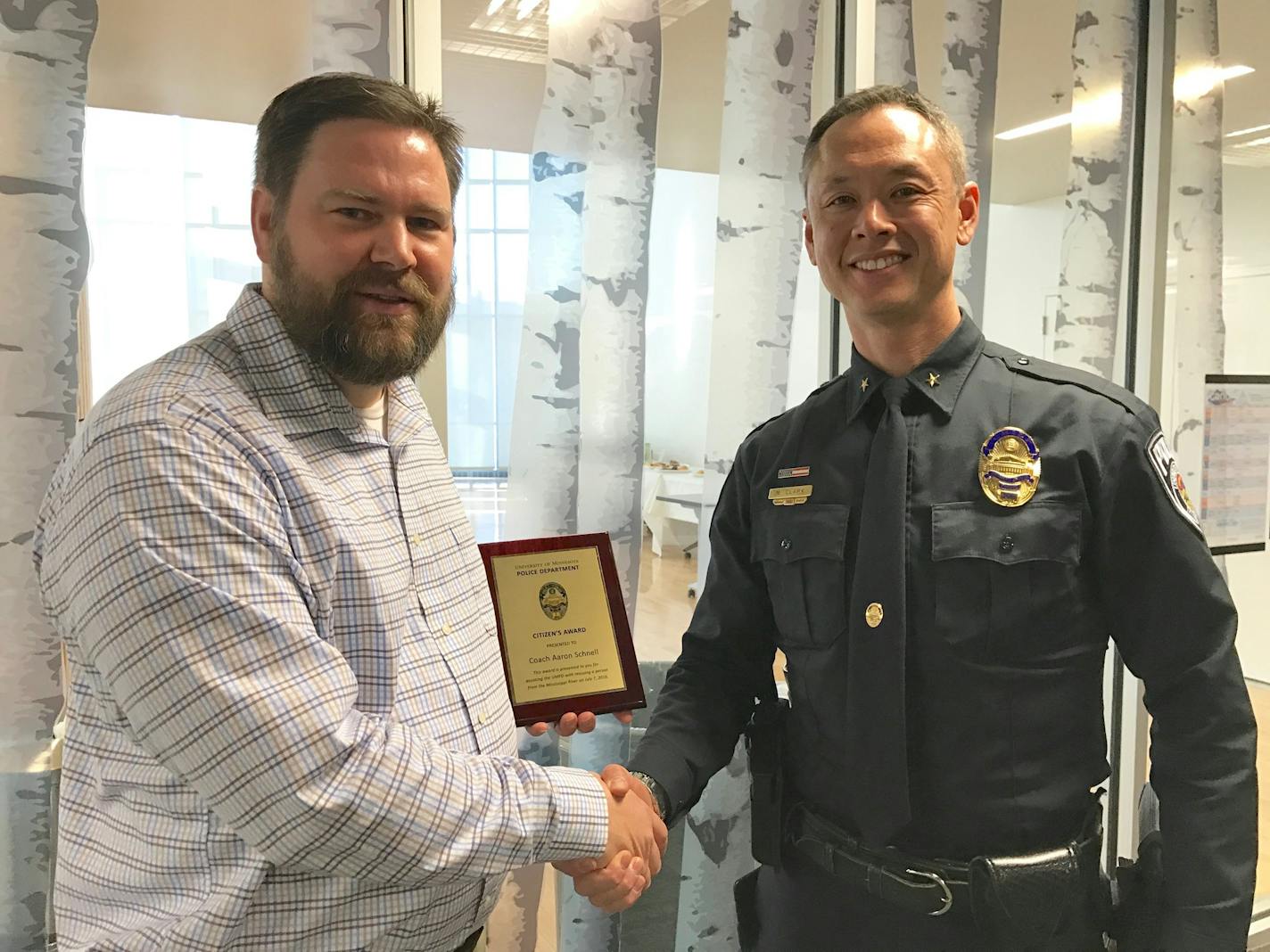 University of Minnesota Police Chief Matt Clark awards men's rowing coach Aaron Schnell with citizen's award Feb. 15, 2017 for helping in July 2016 Mississippi River rescue of bridge jumper. Photo by Jessie Bekker.