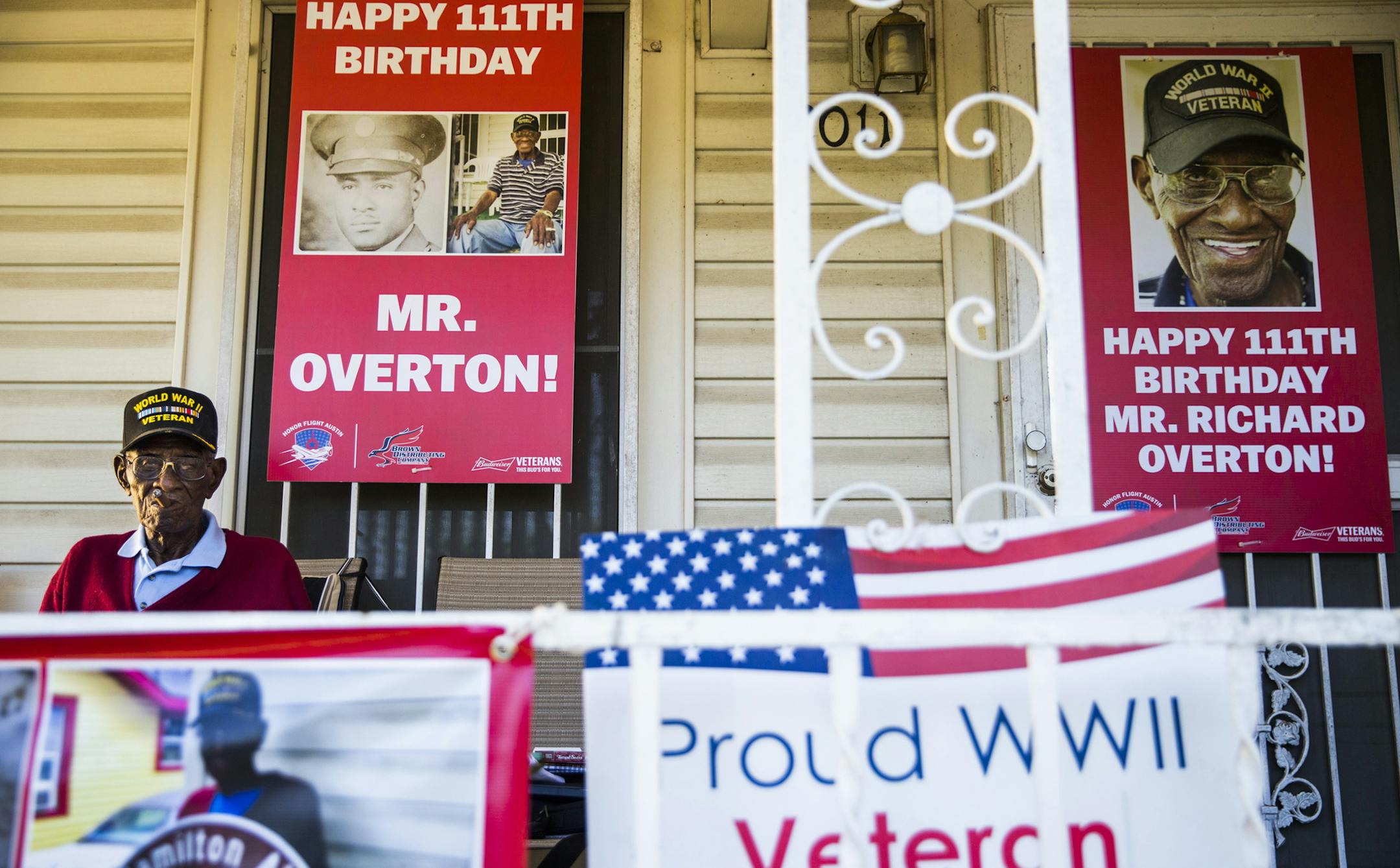 Richard Overton, 111, smokes a cigar on his front porch among signs that were recently displayed to celebrate his birthday.