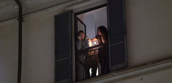 Residents look out from their balcony in Milan, March 15, 2020. Bodies are piling up in Italy as traditional funeral services are illegal throughout t