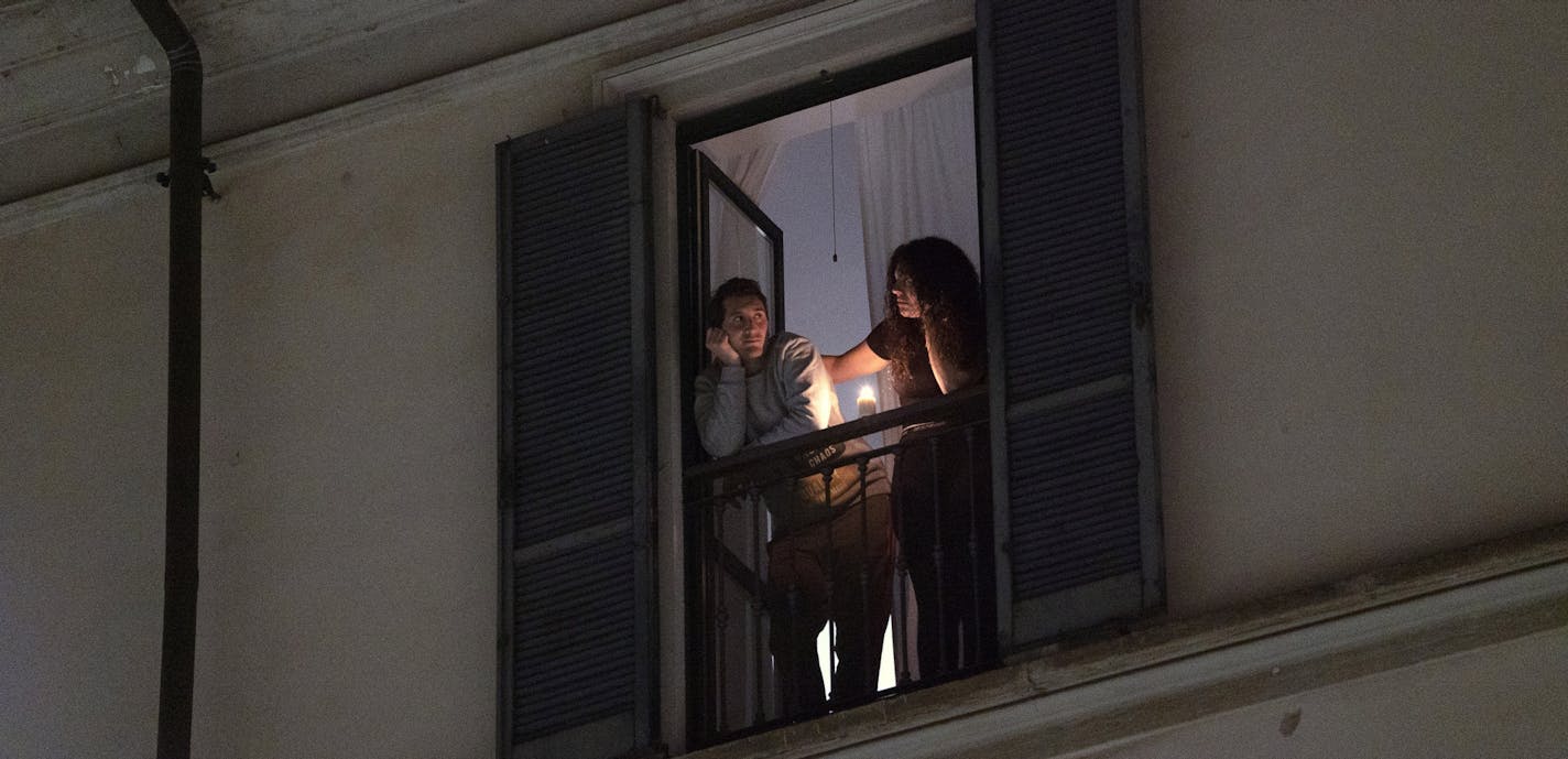 Residents look out from their balcony in Milan, March 15, 2020. Bodies are piling up in Italy as traditional funeral services are illegal throughout the country now, part of the national restrictions against gatherings and going out that have been put in place to try to stem the spread of Europe&#x2019;s worst outbreak of the coronavirus. (Alessandro Grassani/The New York Times)