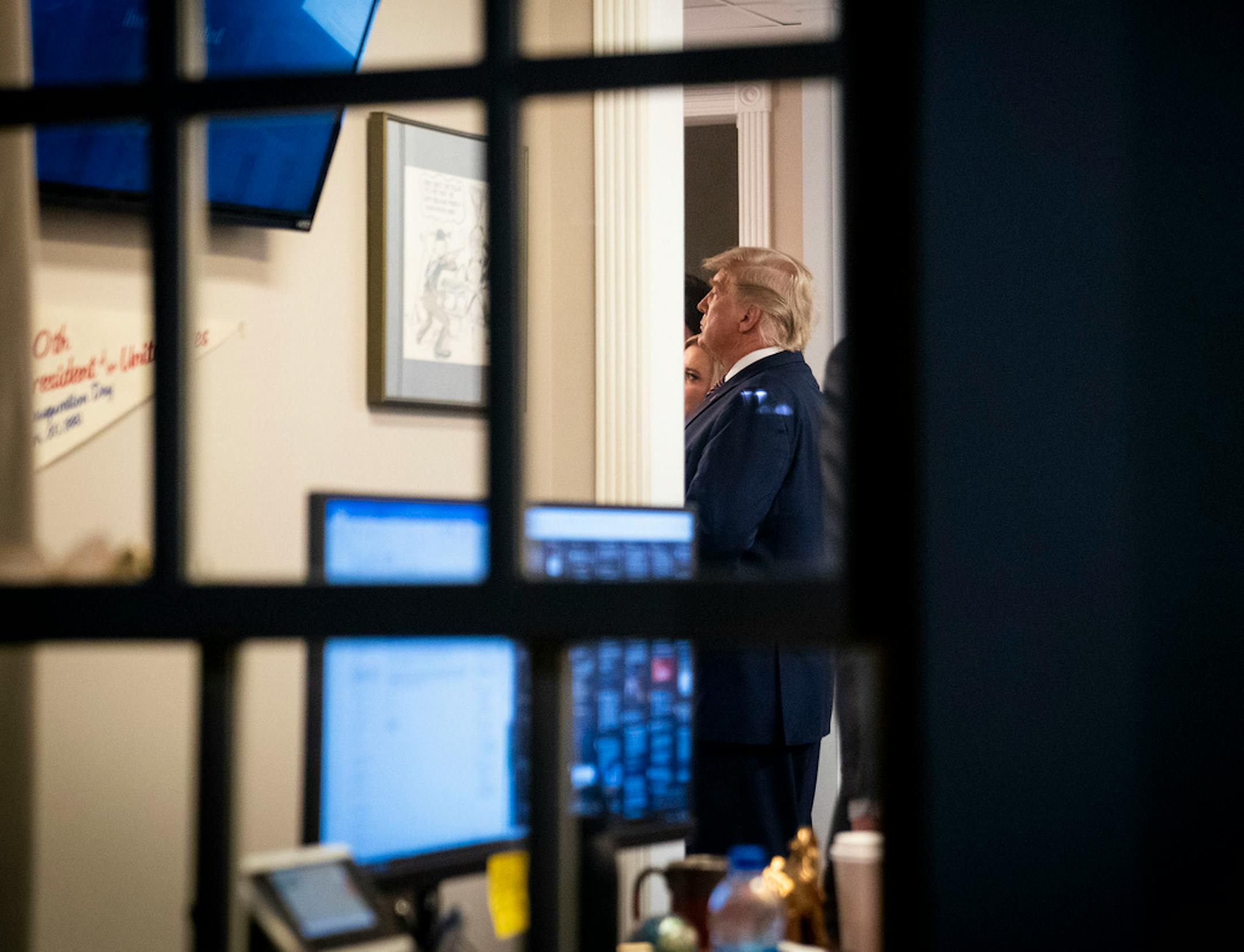 President Donald Trump stands in the press office and watches the TV just minutes after making a statement in the White House in Washington, on Thursday, Nov. 5, 2020.