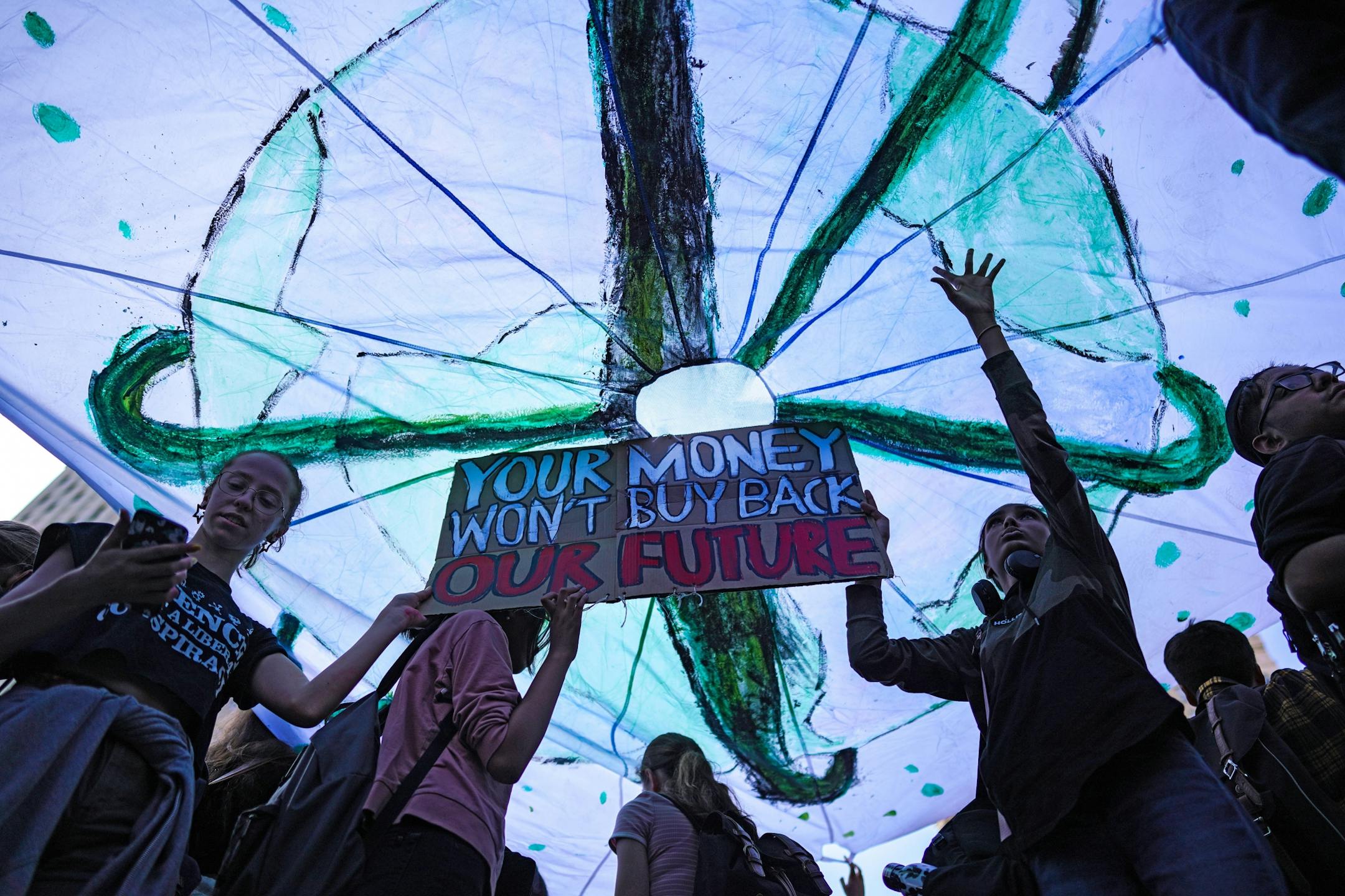 Students from The Bronx High School of the Science hold signs and a decorated parachute cloth during a rally to protest climate change inaction at Foley Square in Manhattan, Sept. 20, 2019. Anxious about their future on a hotter planet, angry at world leaders for failing to arrest the crisis, thousands of young people began pouring into the streets on Friday for a day of global climate protest.