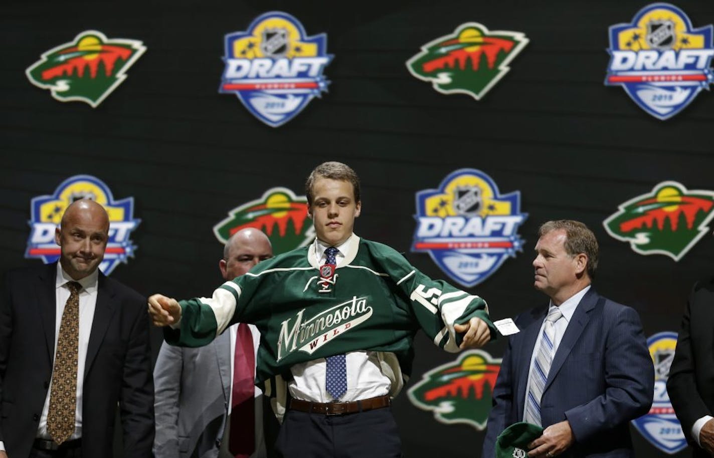 Joel Eriksson Ek, of Sweden, puts on a Minnesota Wild sweater after being chosen 20th overall during the first round of the NHL hockey draft, Friday, June 26, 2015, in Sunrise, Fla.