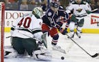 Minnesota Wild's Devan Dubnyk, left, makes a save against Columbus Blue Jackets' Cam Atkinson during the second period of an NHL hockey game Thursday,