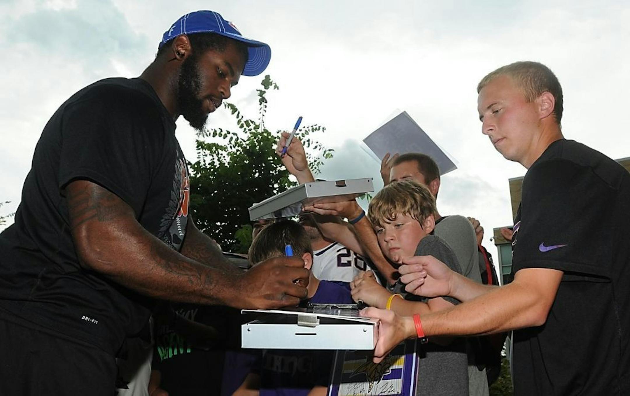 Minnesota Vikings rookie Sharrif Floyd, left, signs autographs after arriving for the NFL football team's training camp on Thursday, July 25, 2013, at Minnesota State University, Mankato.